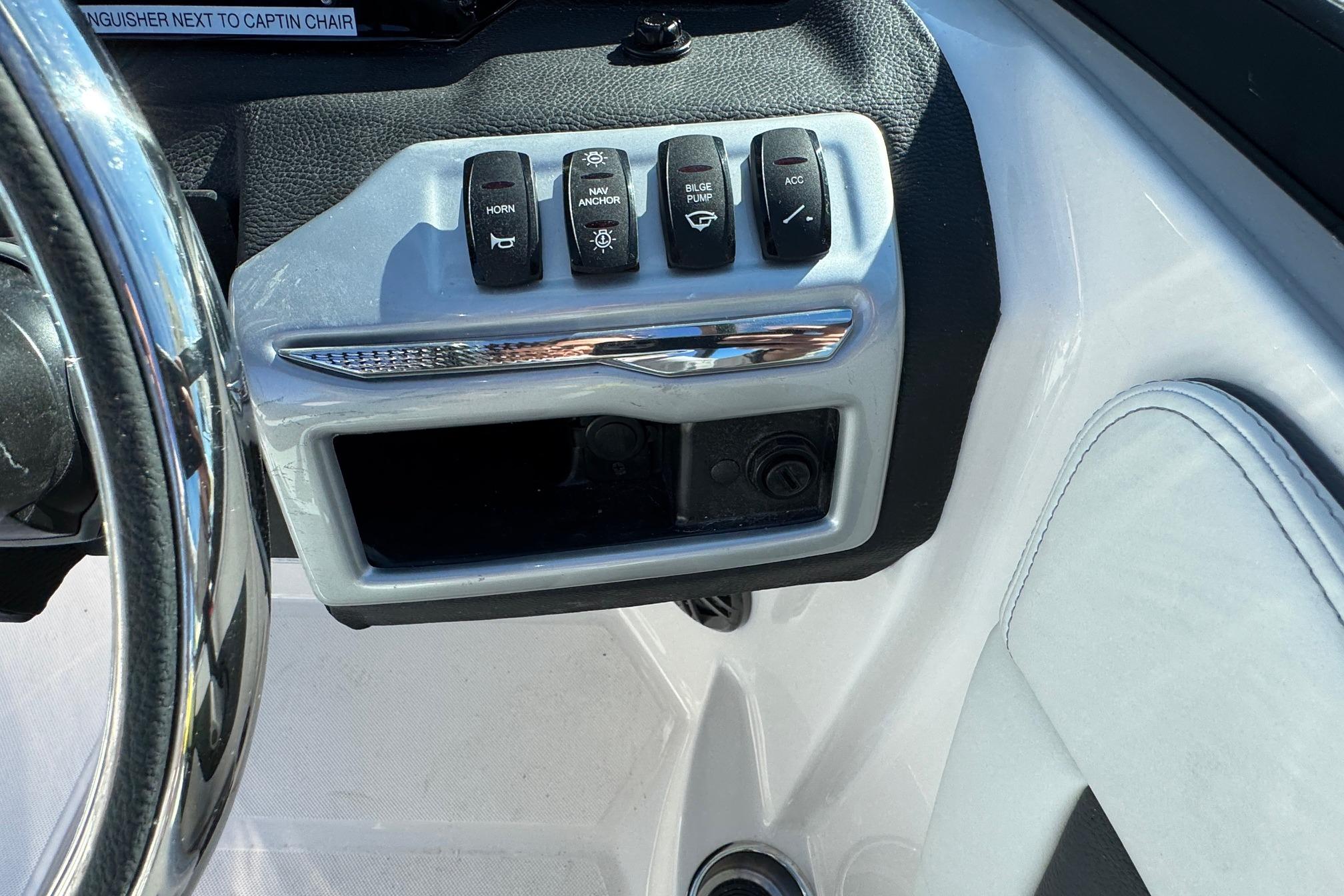 Control panel of 2026 Regal 21 OBX boat with various switches and steering wheel.