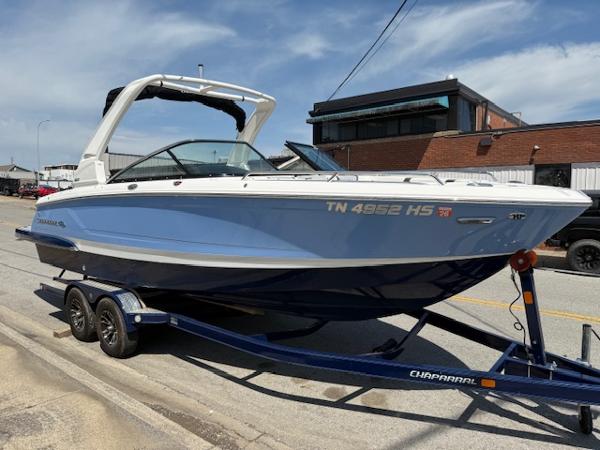2023 Chaparral 267 SSX boat on trailer, parked on street, under clear sky.