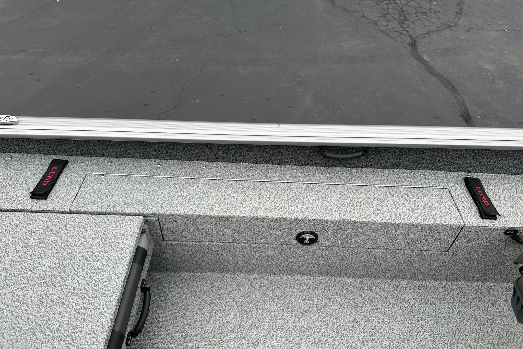 2026 Lund 1875 Impact XS SS boat interior with storage compartments and textured flooring.