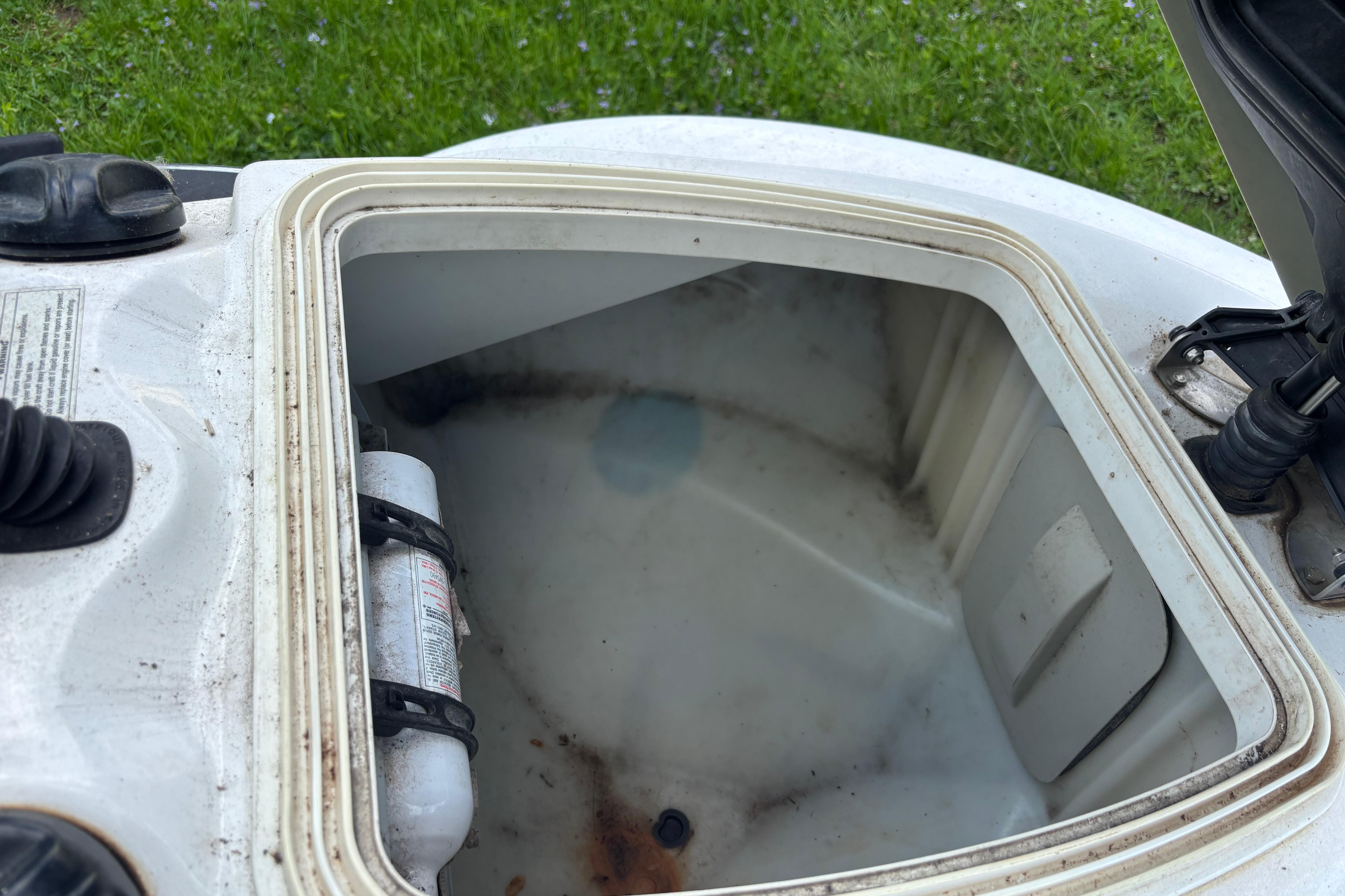 Open storage compartment of a 2002 Sea-Doo GTX DI, showing interior and fire extinguisher.