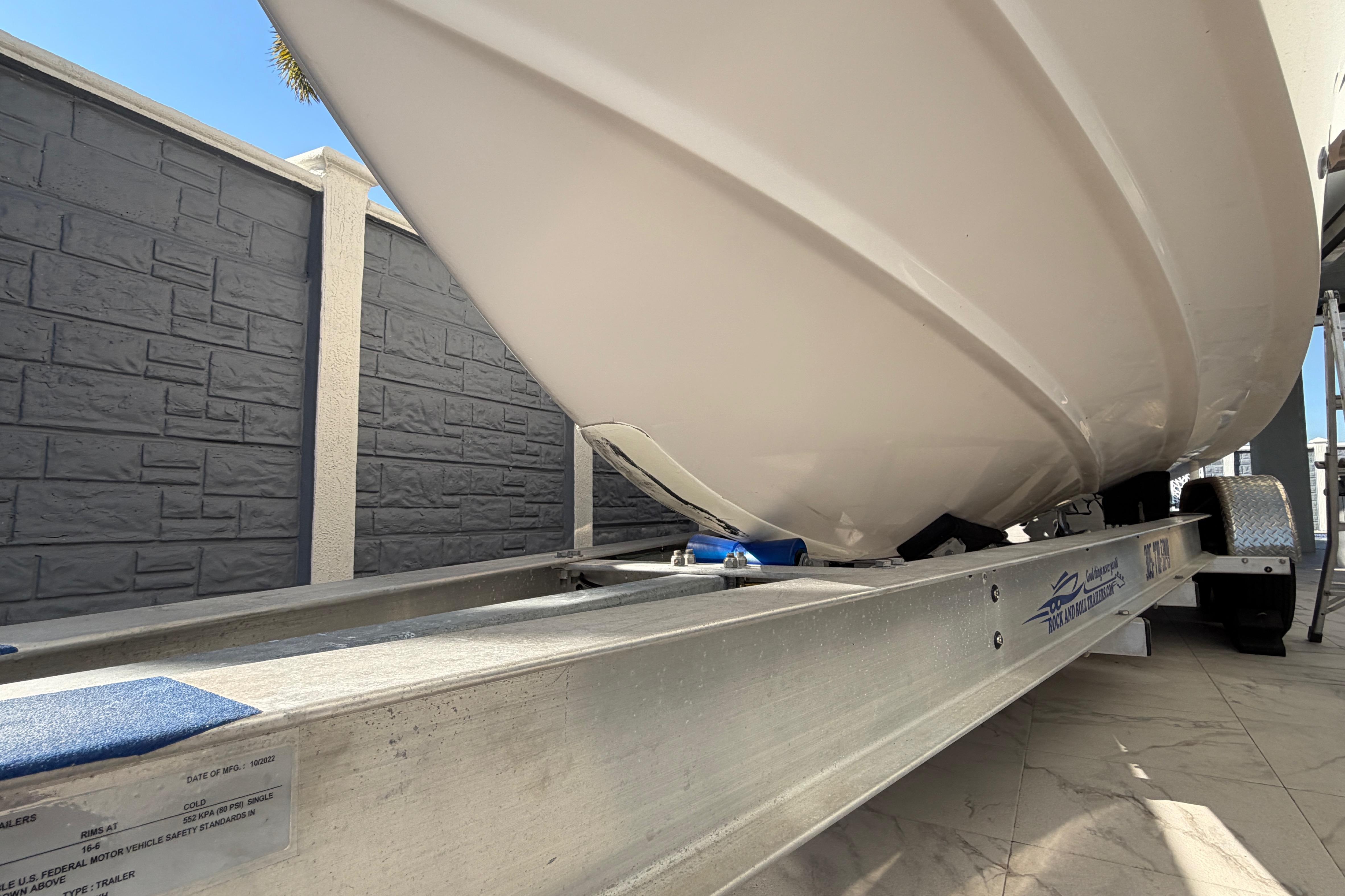 2004 Grady White 273 boat on trailer, viewed from below, against a stone wall background.