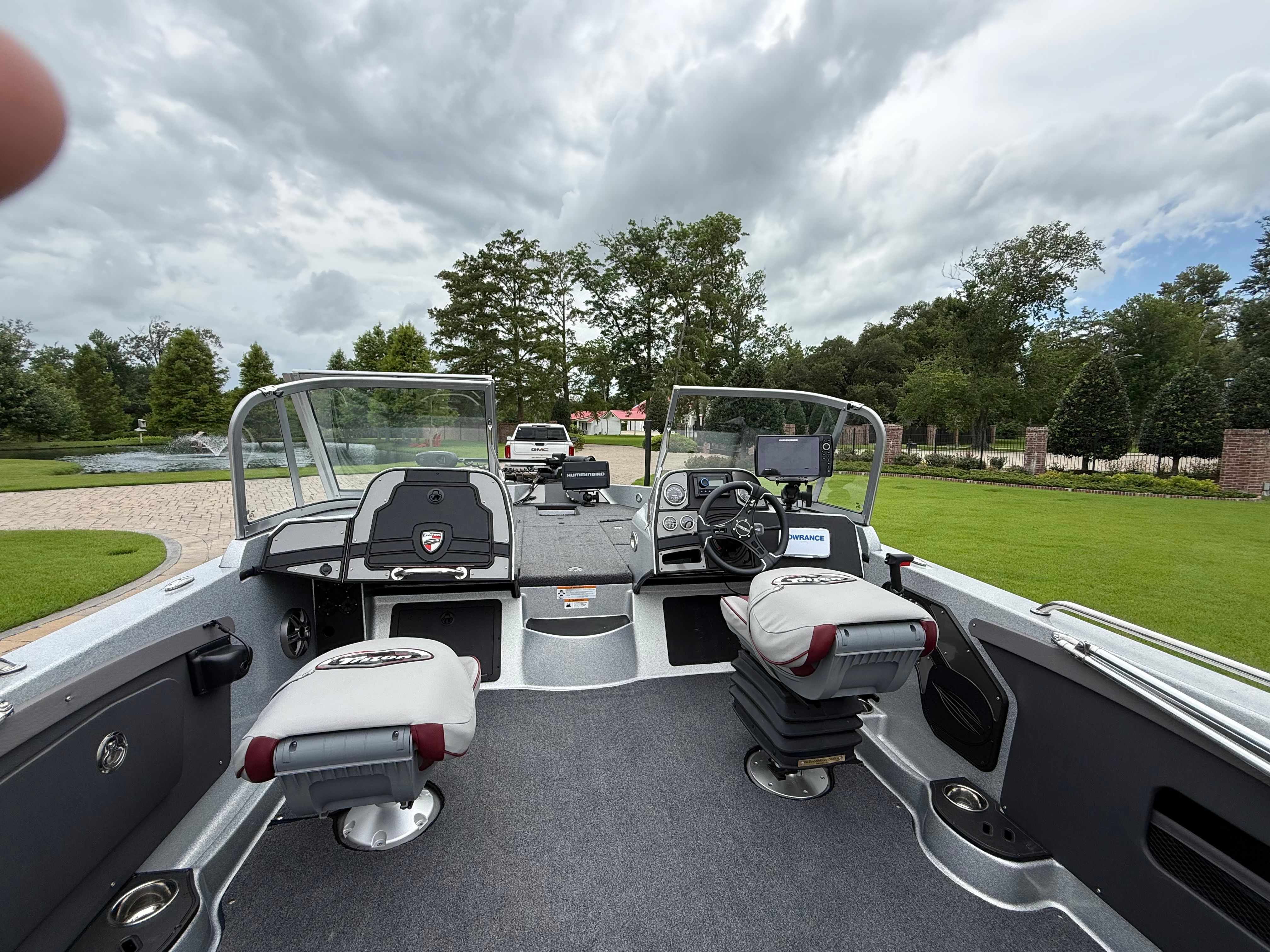 The image shows the cockpit of a 2023 Triton 206 Allure boat with two seats and a helm.