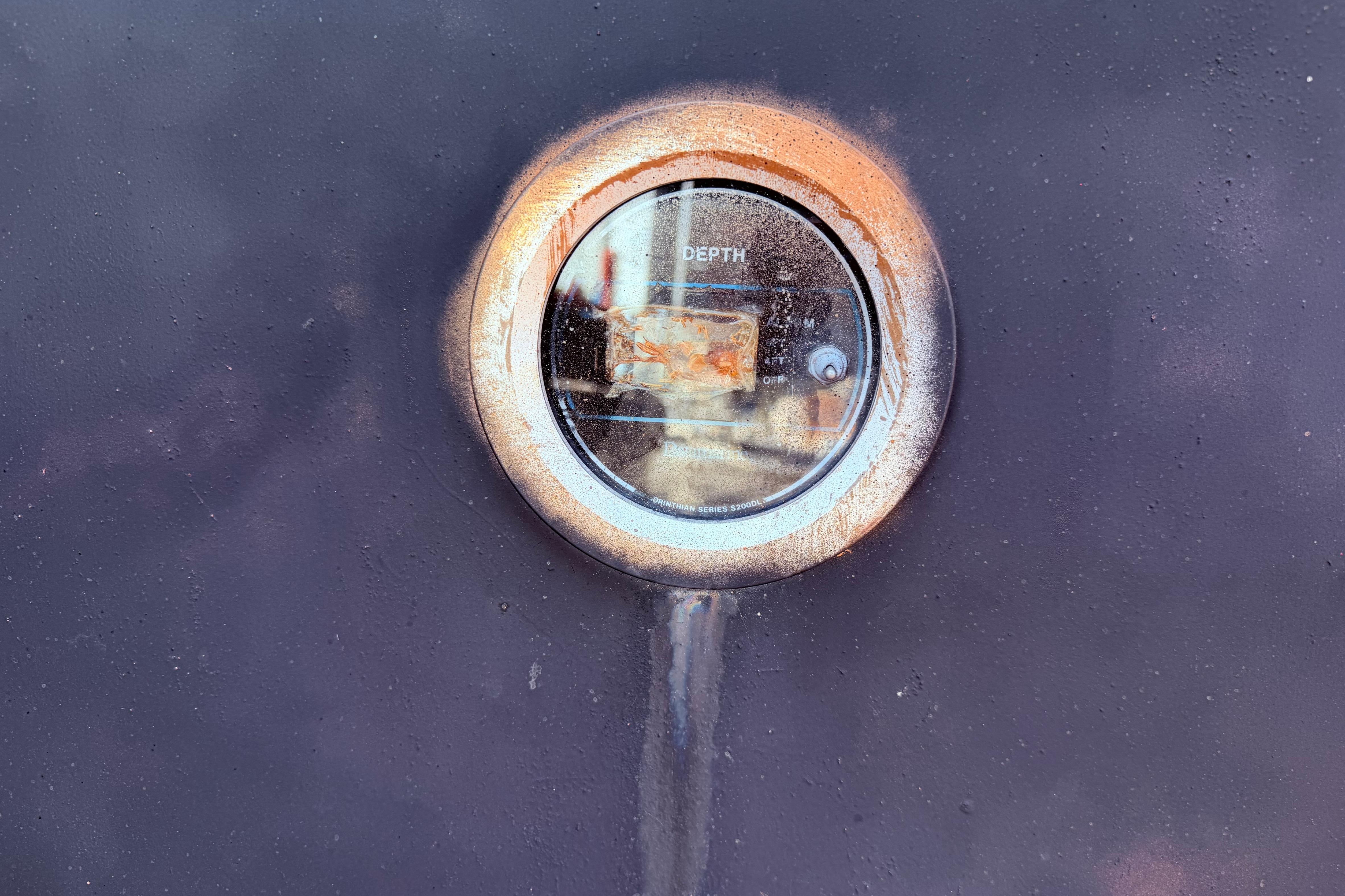 Depth gauge on 1982 Watkins 27 Pirate Ship, showing weathered exterior.