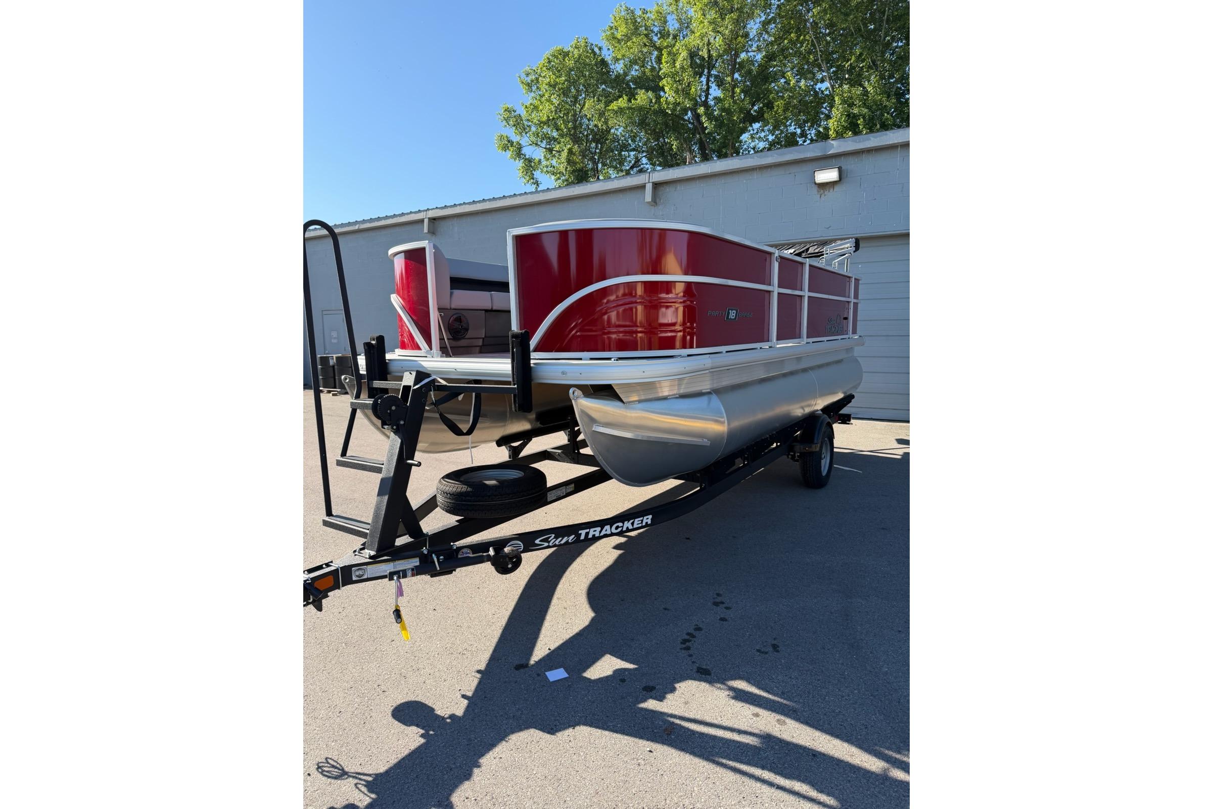 2026 Sun Tracker Party Barge 18 DLX pontoon boat on trailer, parked outdoors.