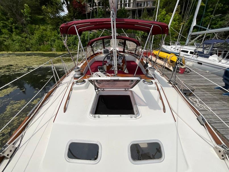 1980 Gulfstar 44 Center Cockpit sailboat docked, featuring red canopy and open hatch.