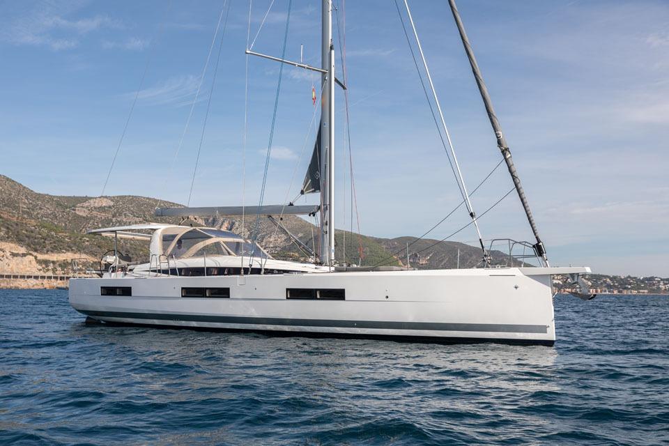 2023 Jeanneau 60 yacht sailing on calm waters with scenic coastal backdrop.