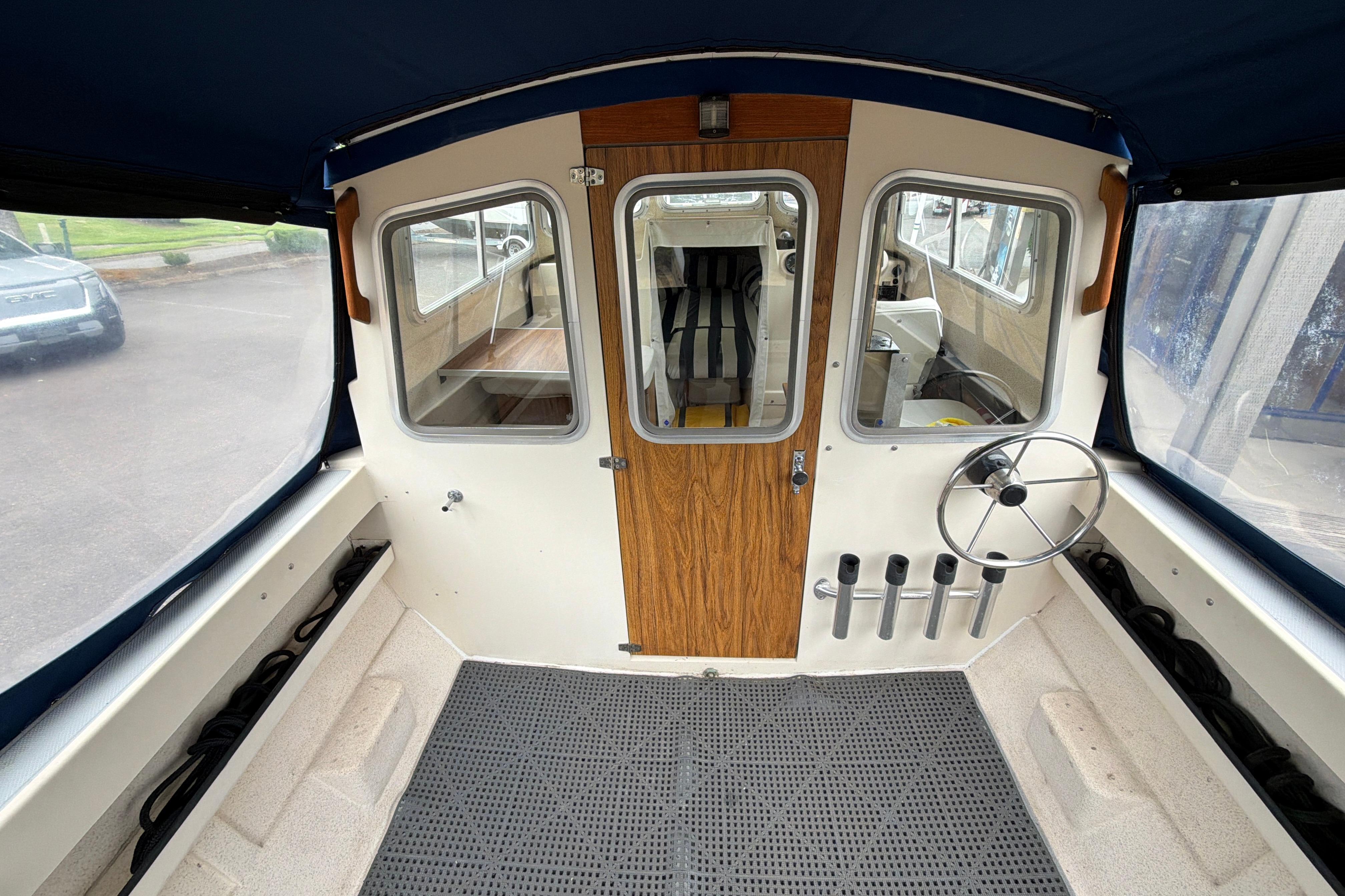 1989 C-Dory 22' Angler boat interior with steering wheel, rod holders, and cabin view.