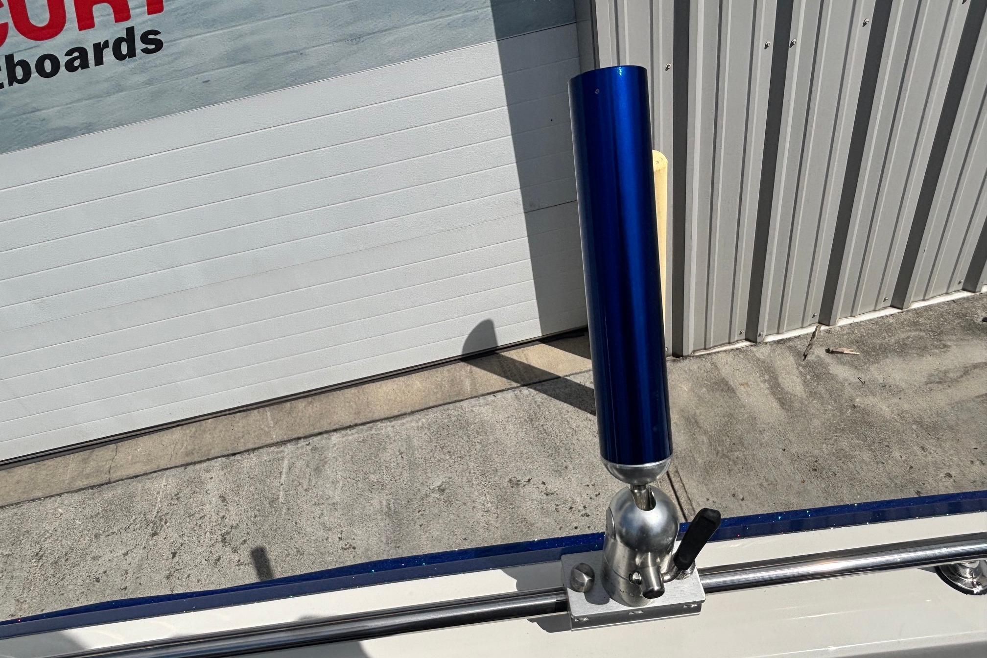 Blue rod holder on 2022 Ranger 1880MS boat, near metal building.