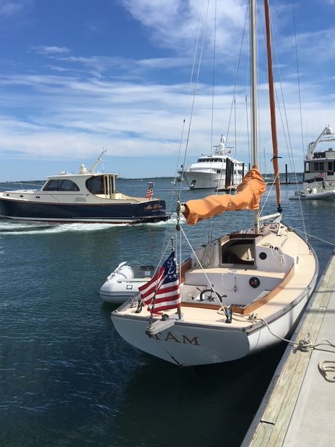 A sailboat with an American flag docked, surrounded by other boats.