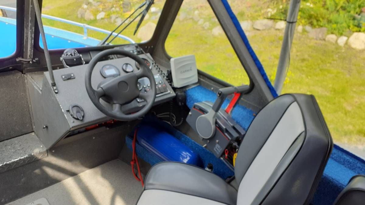 Interior view of a boat with steering console and seat.