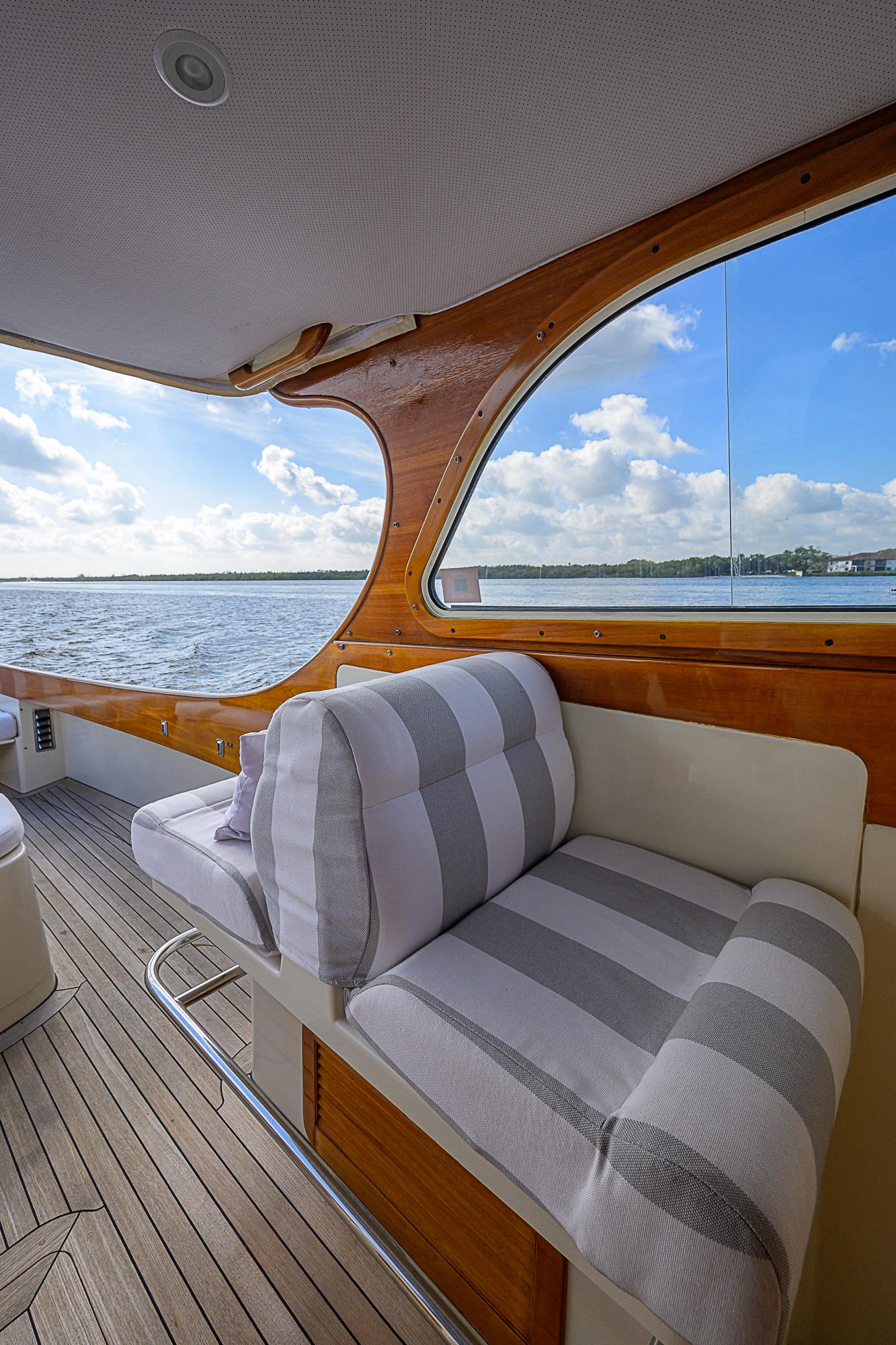 Hinckley Picnic Boat Classic 2000 interior with striped seating, wooden accents, and scenic water view.
