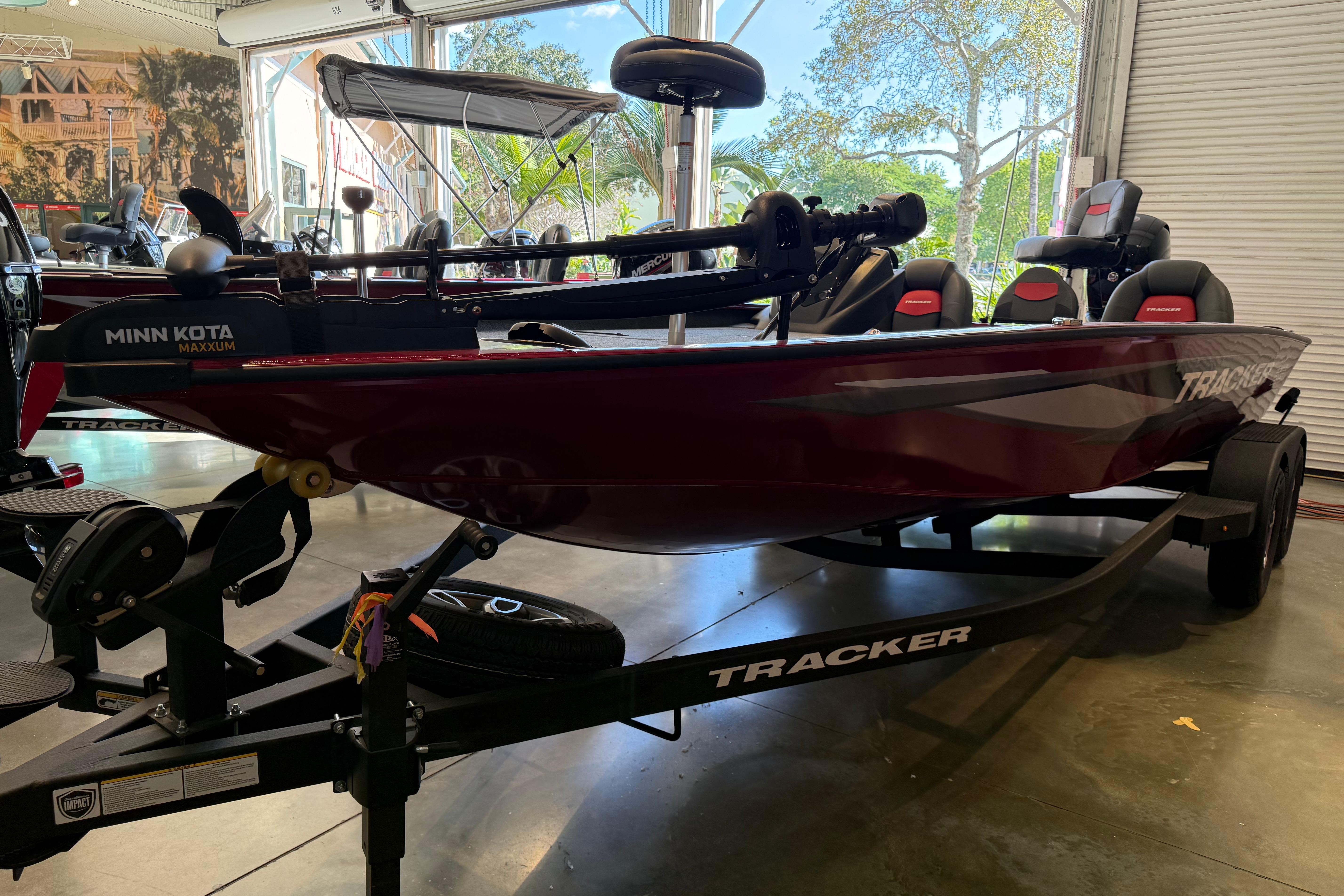 2025 Tracker Savage 215 boat on trailer in showroom, featuring Minn Kota Maxxum motor.