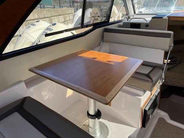 Interior of 2025 Cutwater C-248 C Coupe with wooden table and cushioned seating.