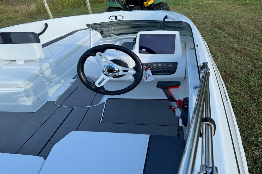 2026 Tahoe T16 boat interior with steering wheel and control panel, parked on grass.