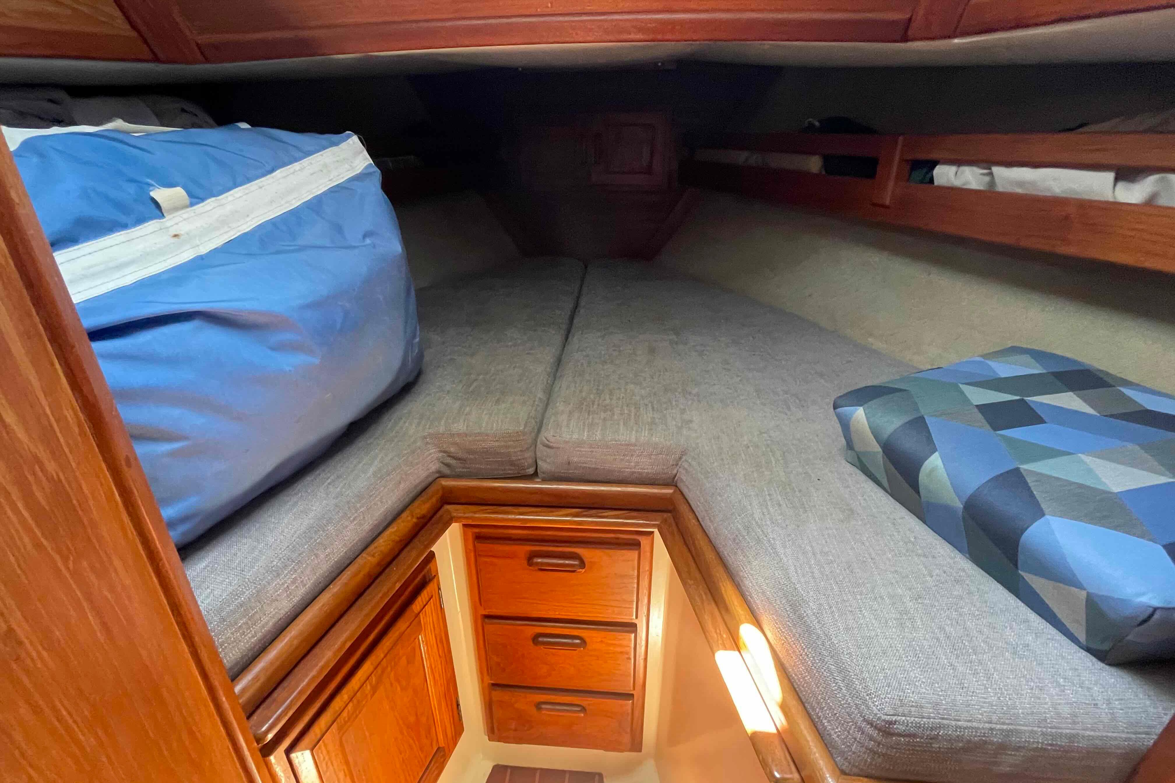 Cozy cabin interior of 1987 Pacific Seacraft 34 sailboat with bedding and storage drawers.