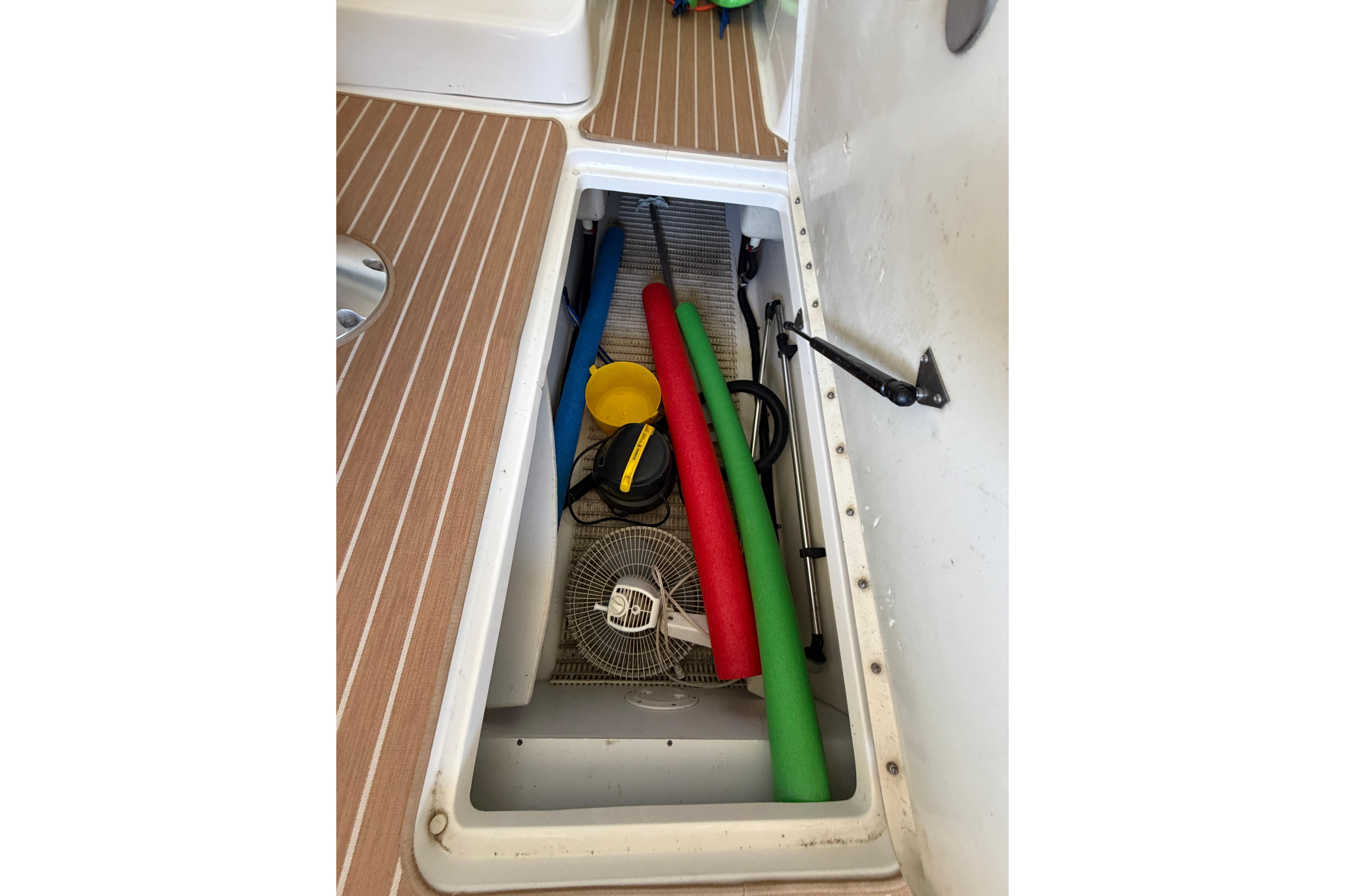 Storage compartment of a 2007 Sea Ray 270 SLX boat with pool noodles and accessories.