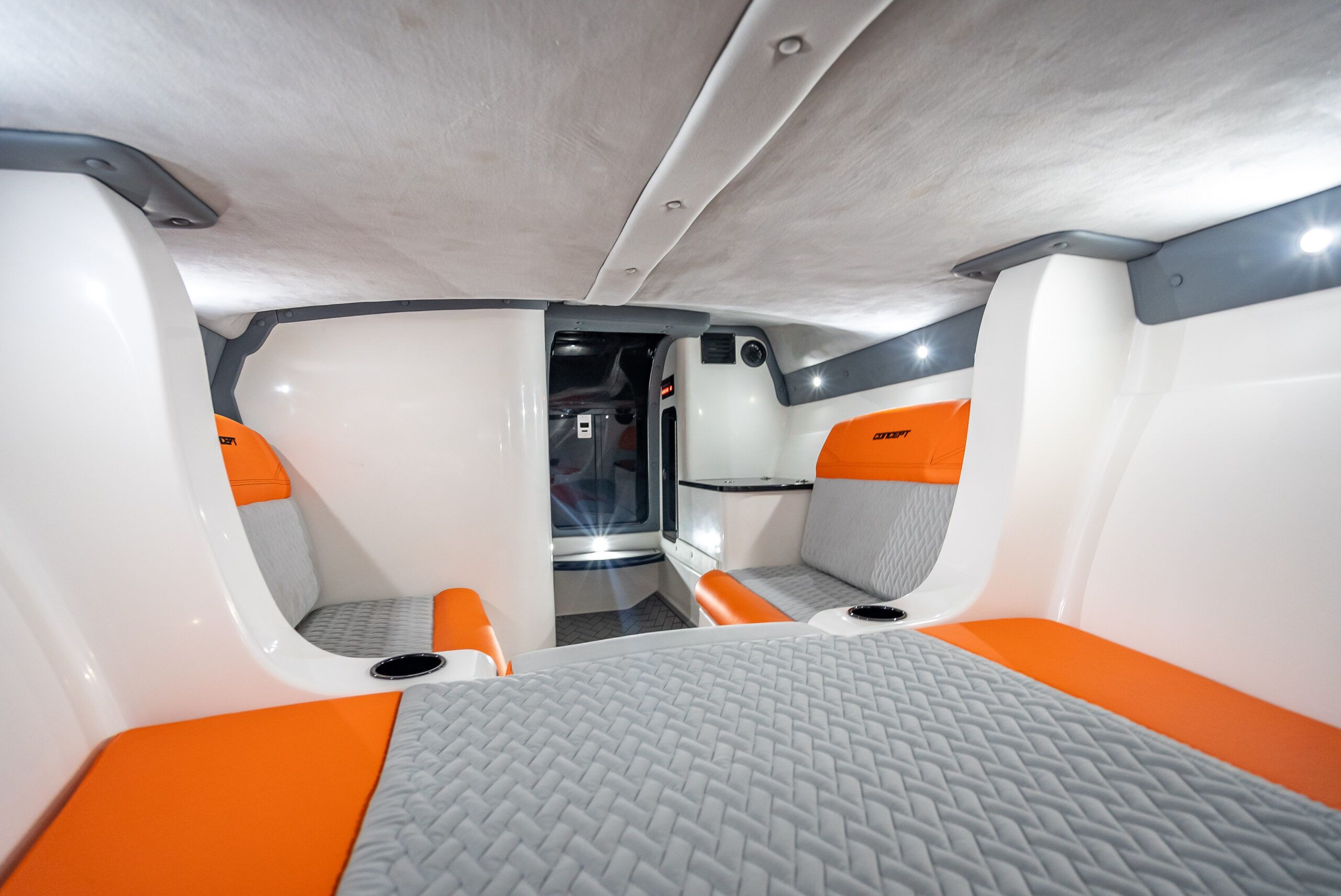 Interior of a modern boat with orange and gray seating and white walls.