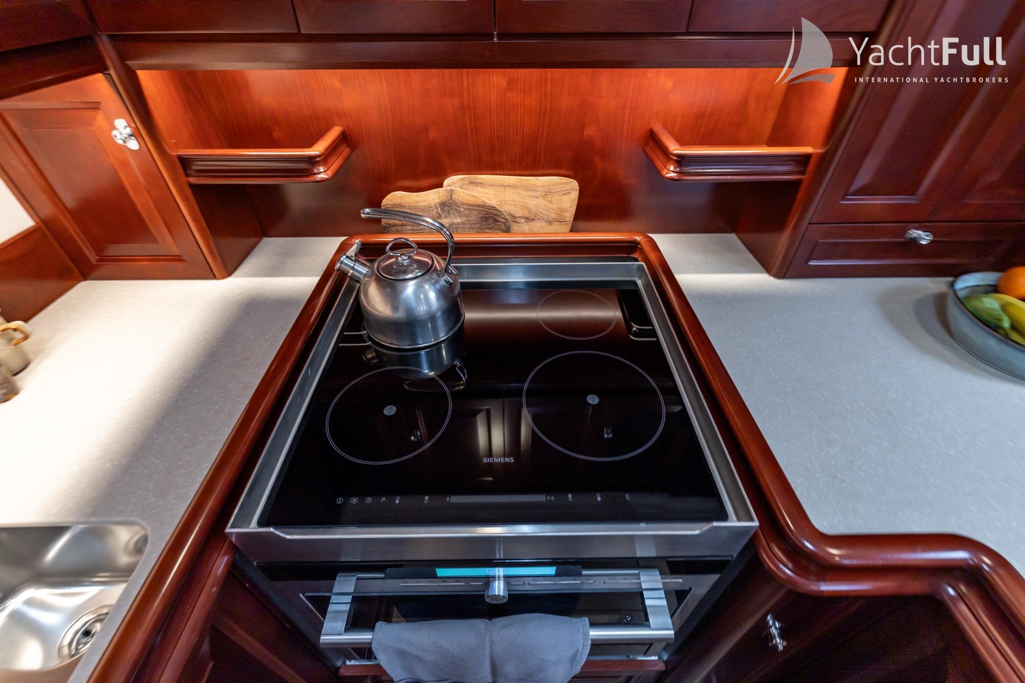 Modern yacht kitchen with induction stove, kettle, and wooden cabinetry. Dykstra 73, 2025 model.