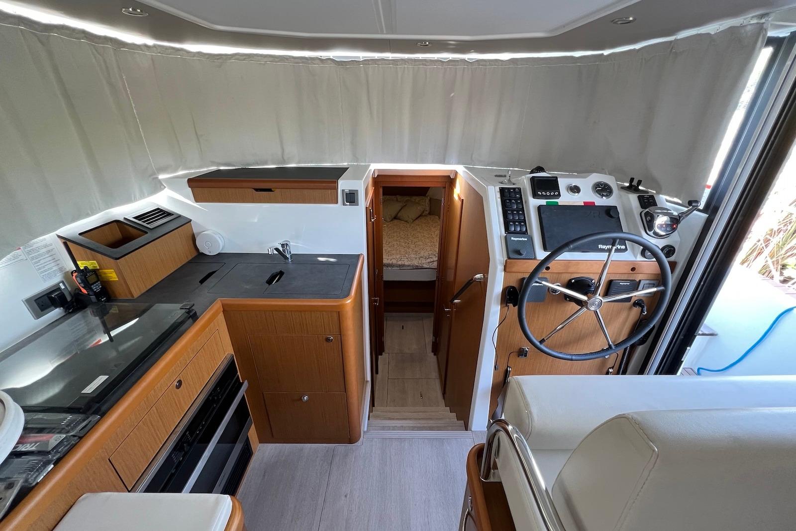 Interior of 2020 Beneteau Swift Trawler 35, featuring helm, kitchen, and cabin entrance.