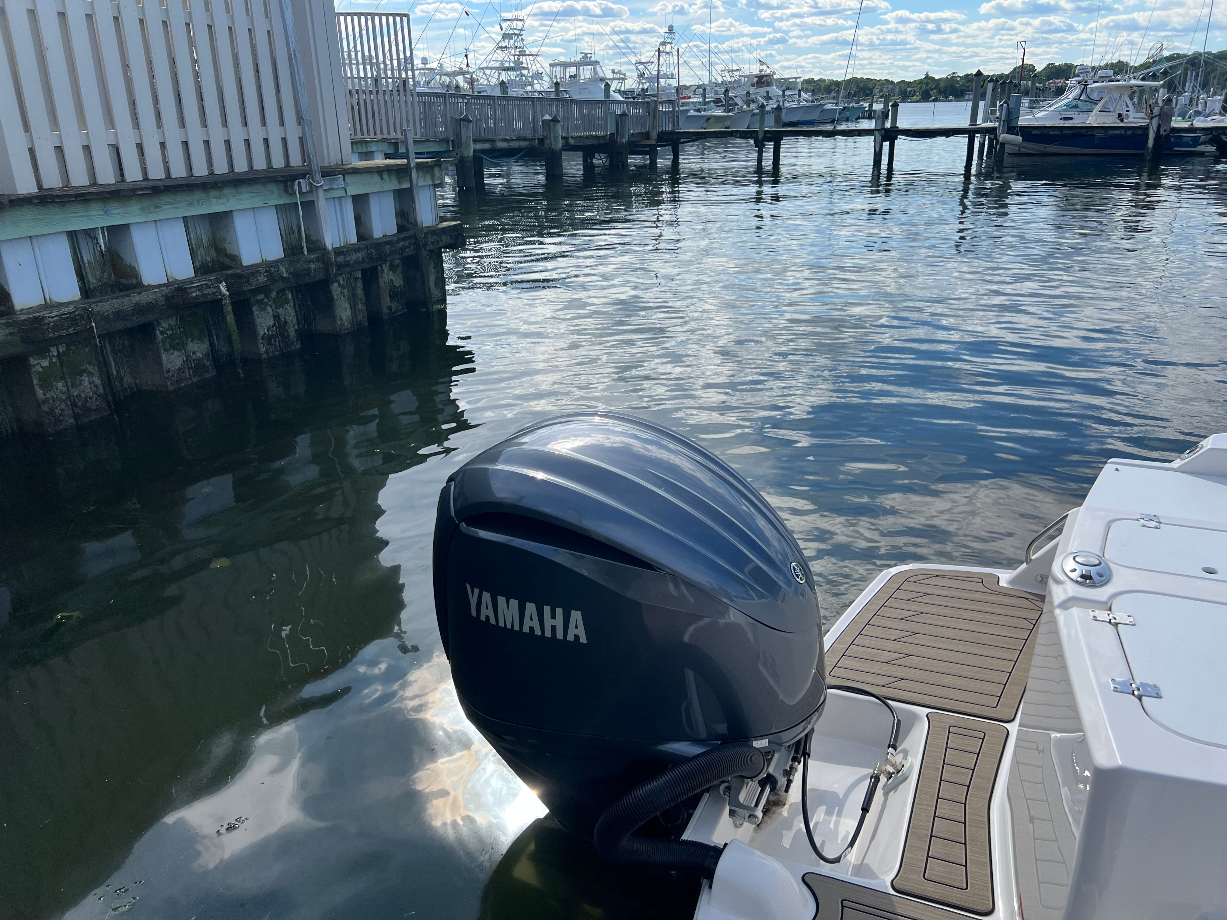 A Yamaha outboard motor on a boat in a harbor, surrounded by water and other boats.