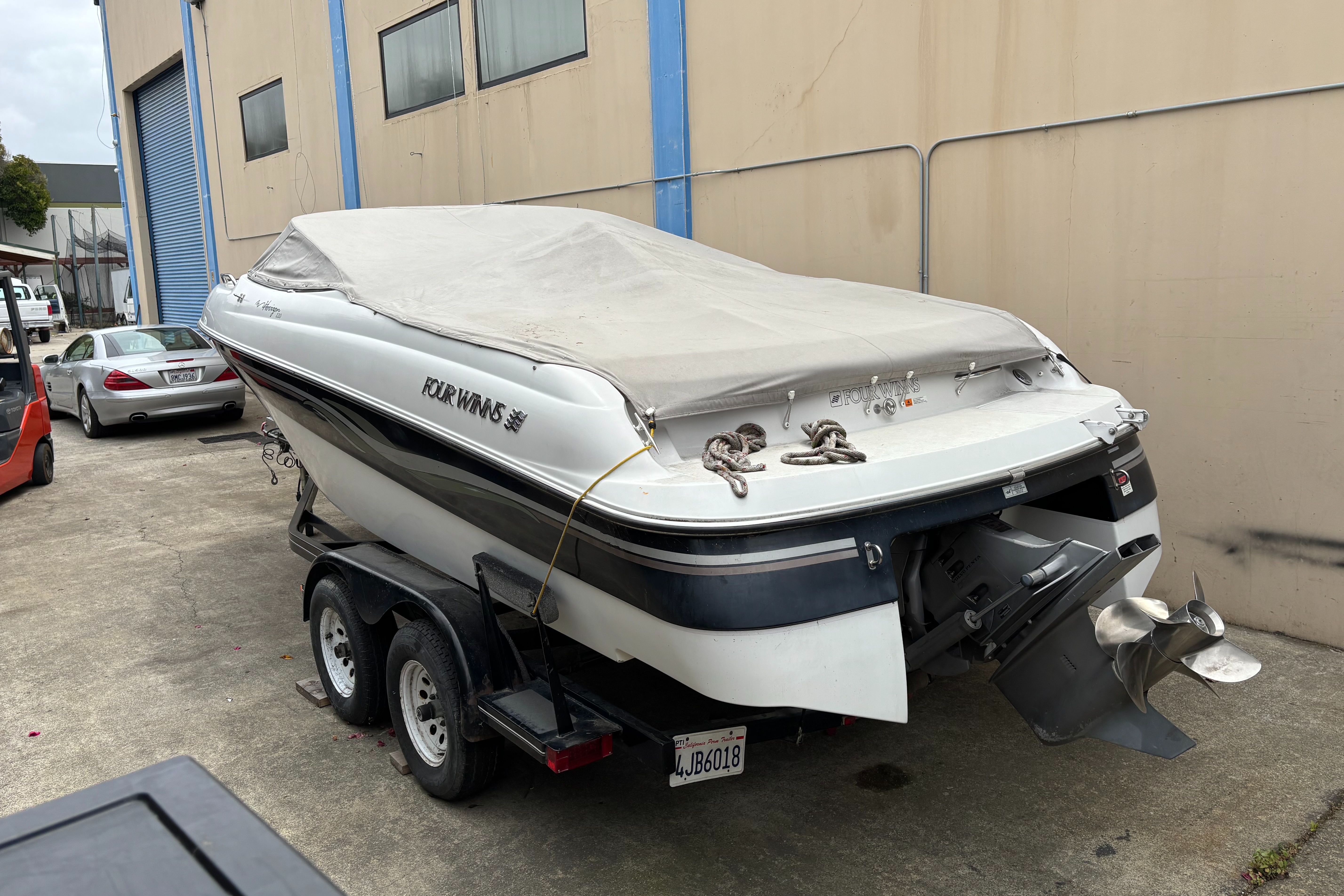 A 2000 Four Winns 220 Horizon boat on a trailer, covered and parked.