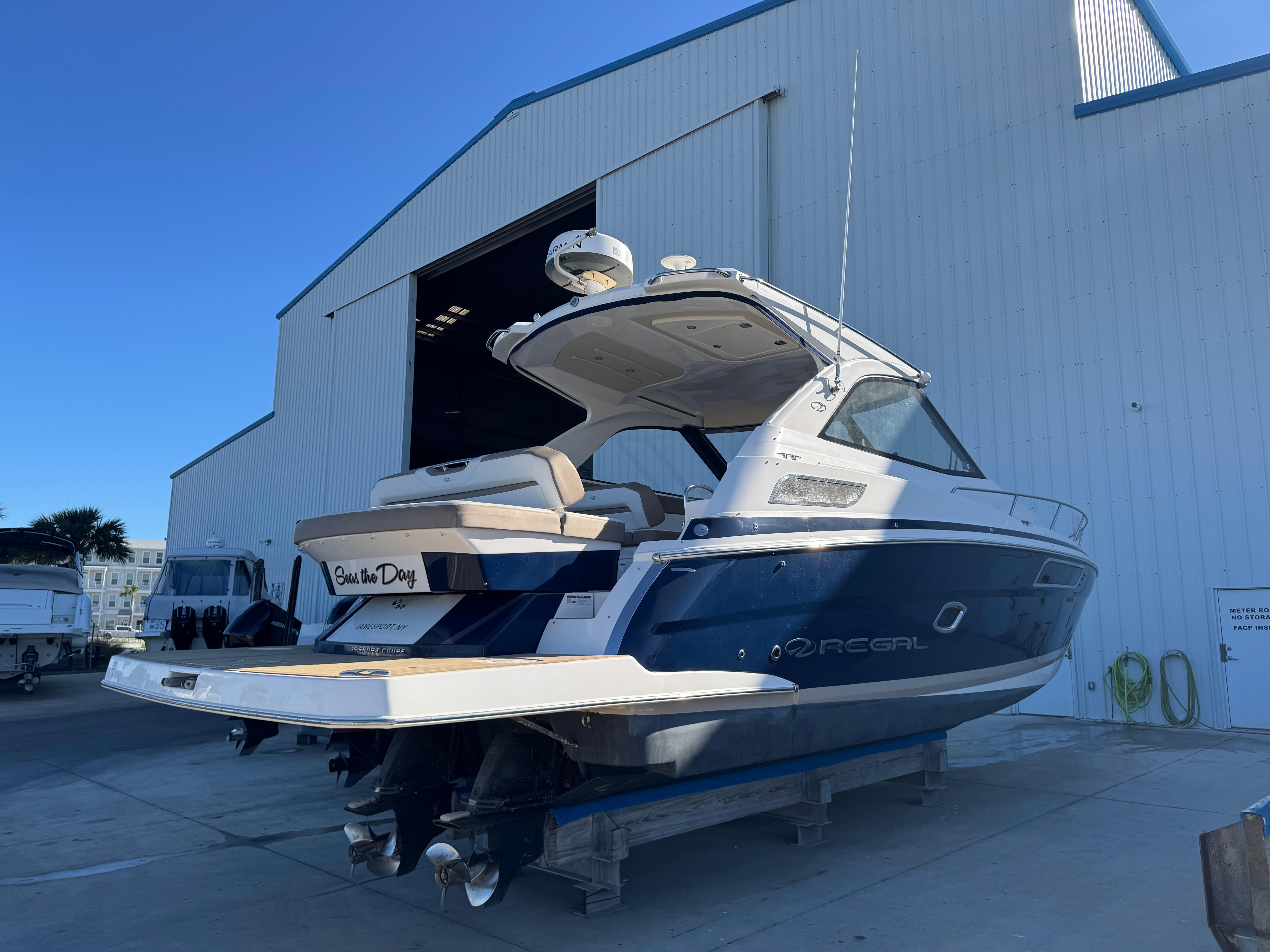 2016 Regal 35 Sport Coupe boat docked near a large warehouse.