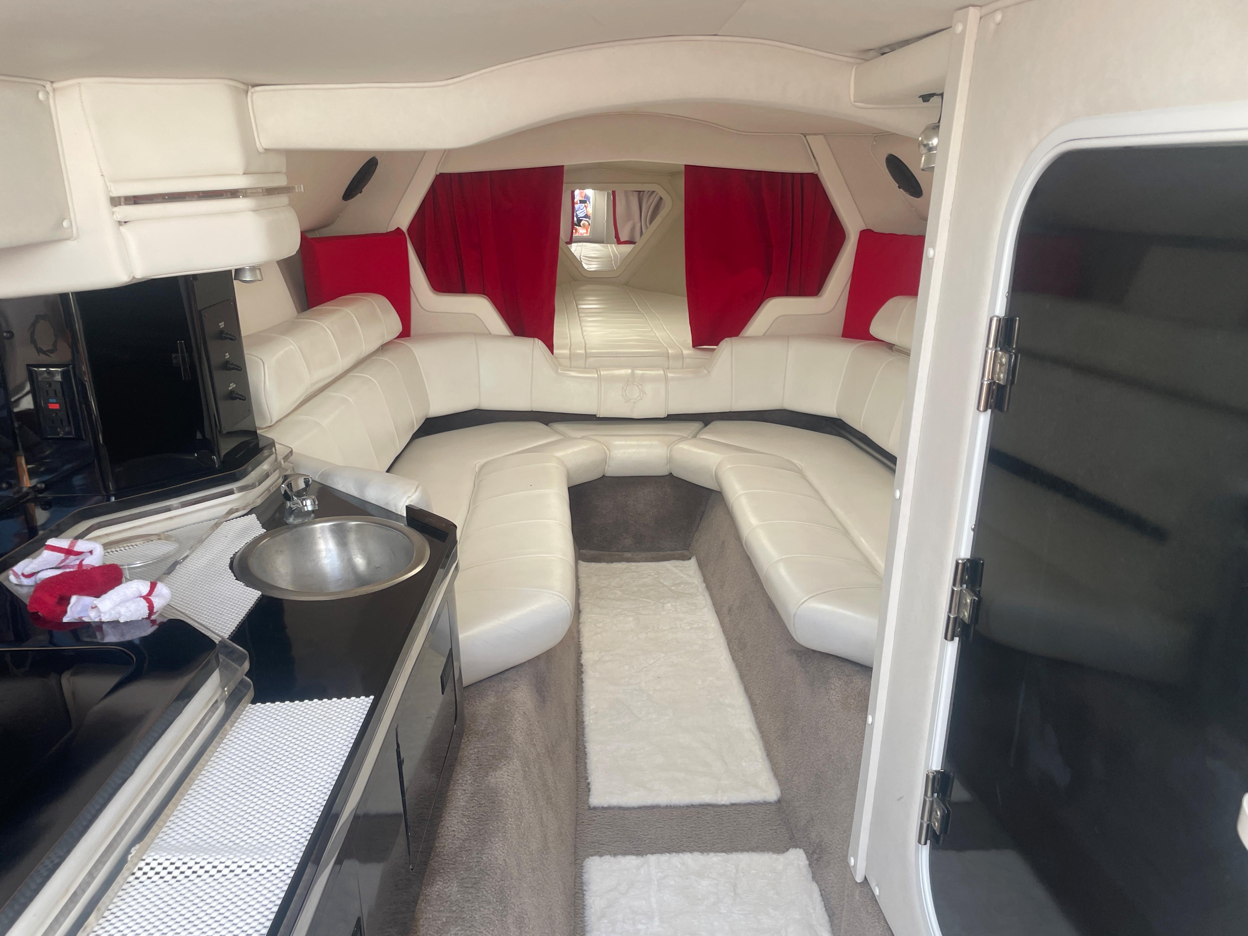 1995 Fountain 42 Executioner boat interior with white leather seating and red curtains.