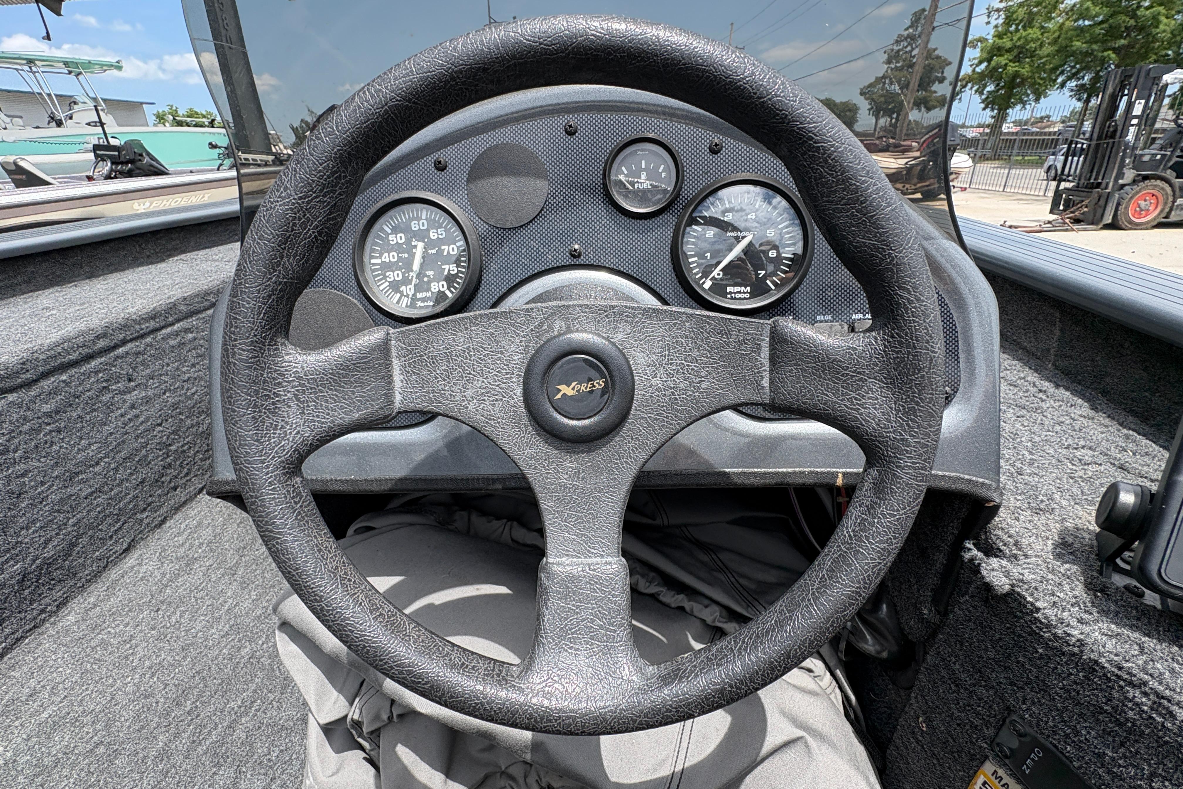 Steering wheel and dashboard of a 2000 Xpress X18 boat, featuring gauges and controls.