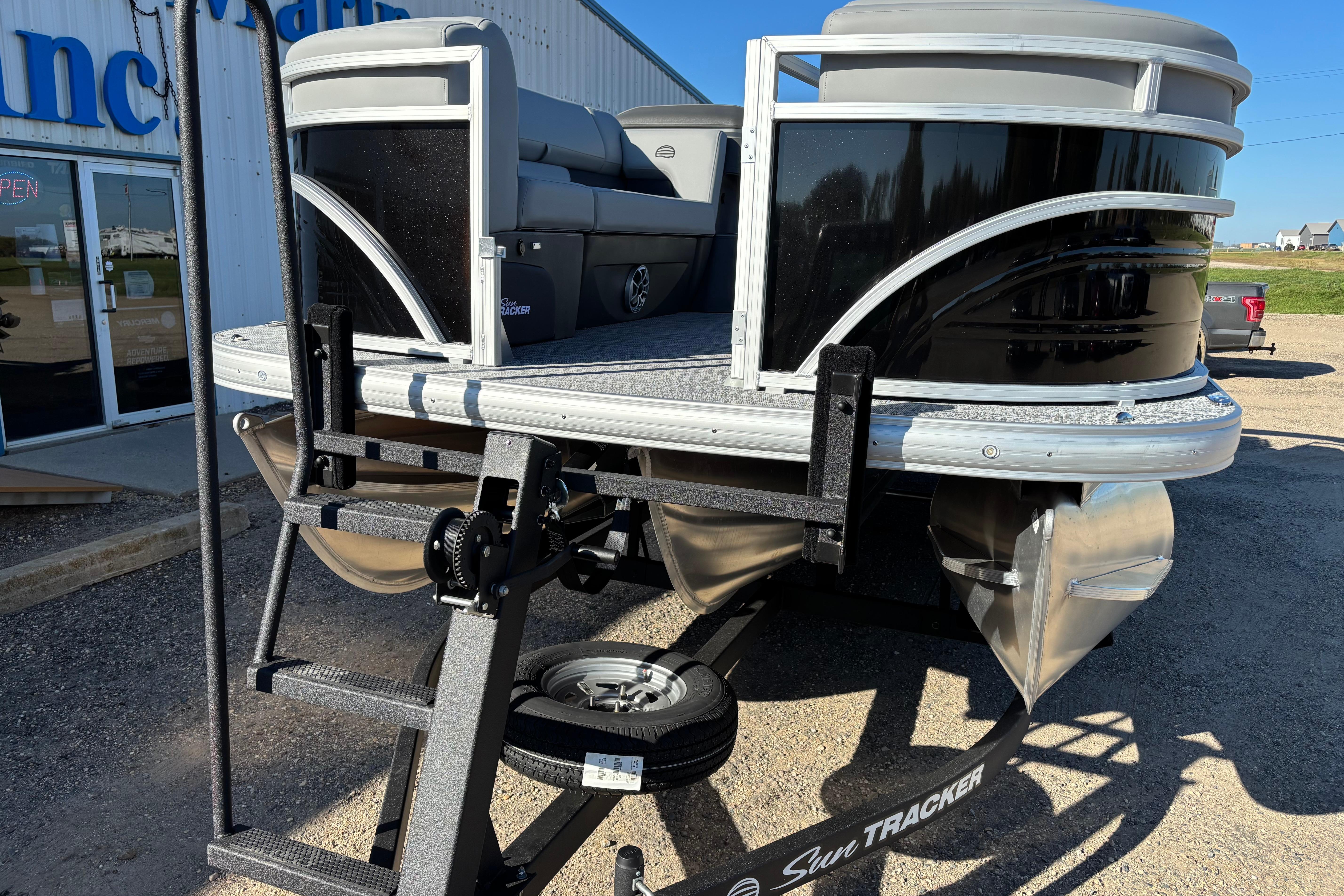 2026 Sun Tracker SportFish 22 XP3 pontoon boat on trailer, parked outside dealership.