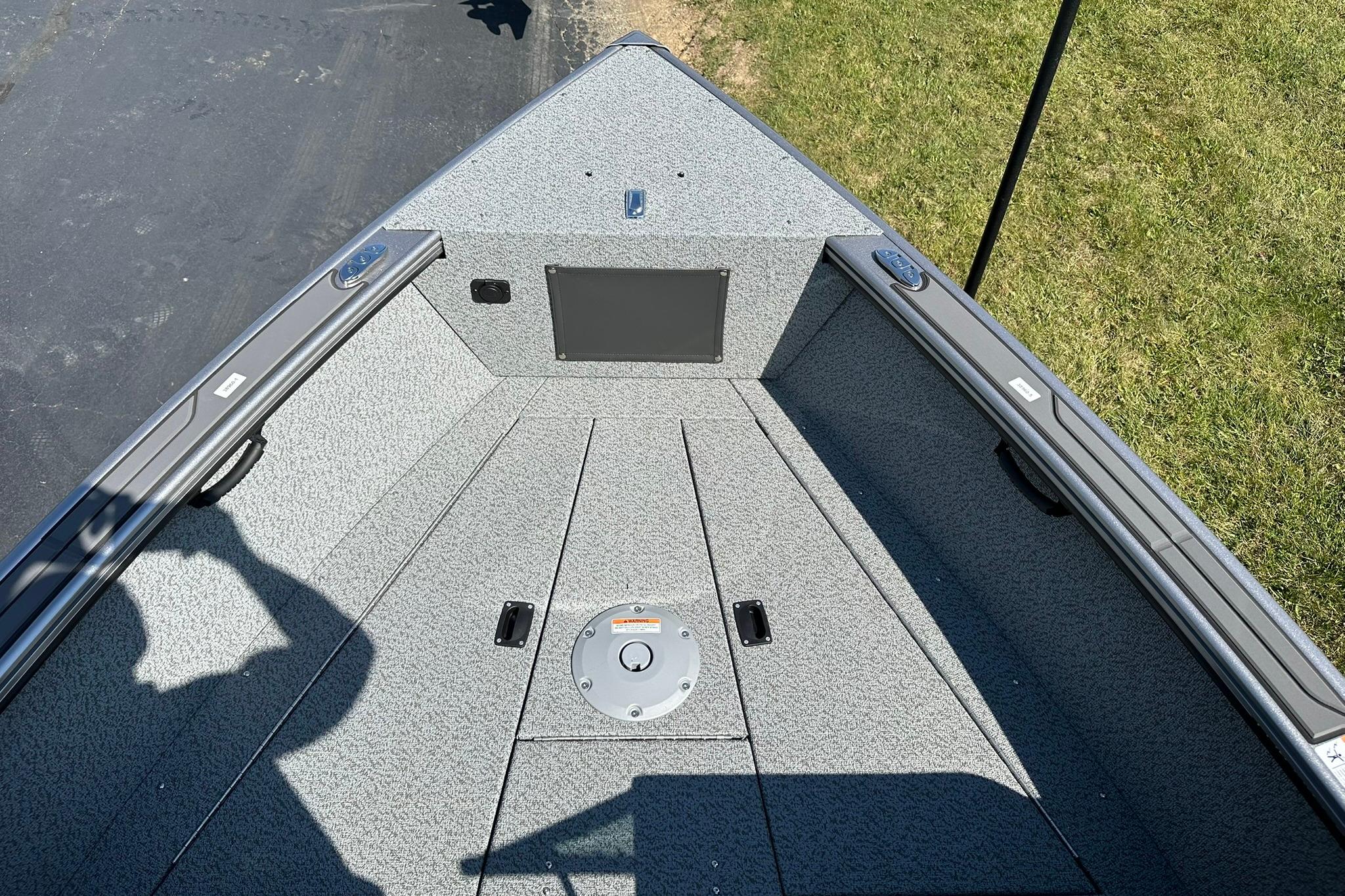 2026 Lund 1875 Fisherman boat interior with gray textured flooring and storage compartments.