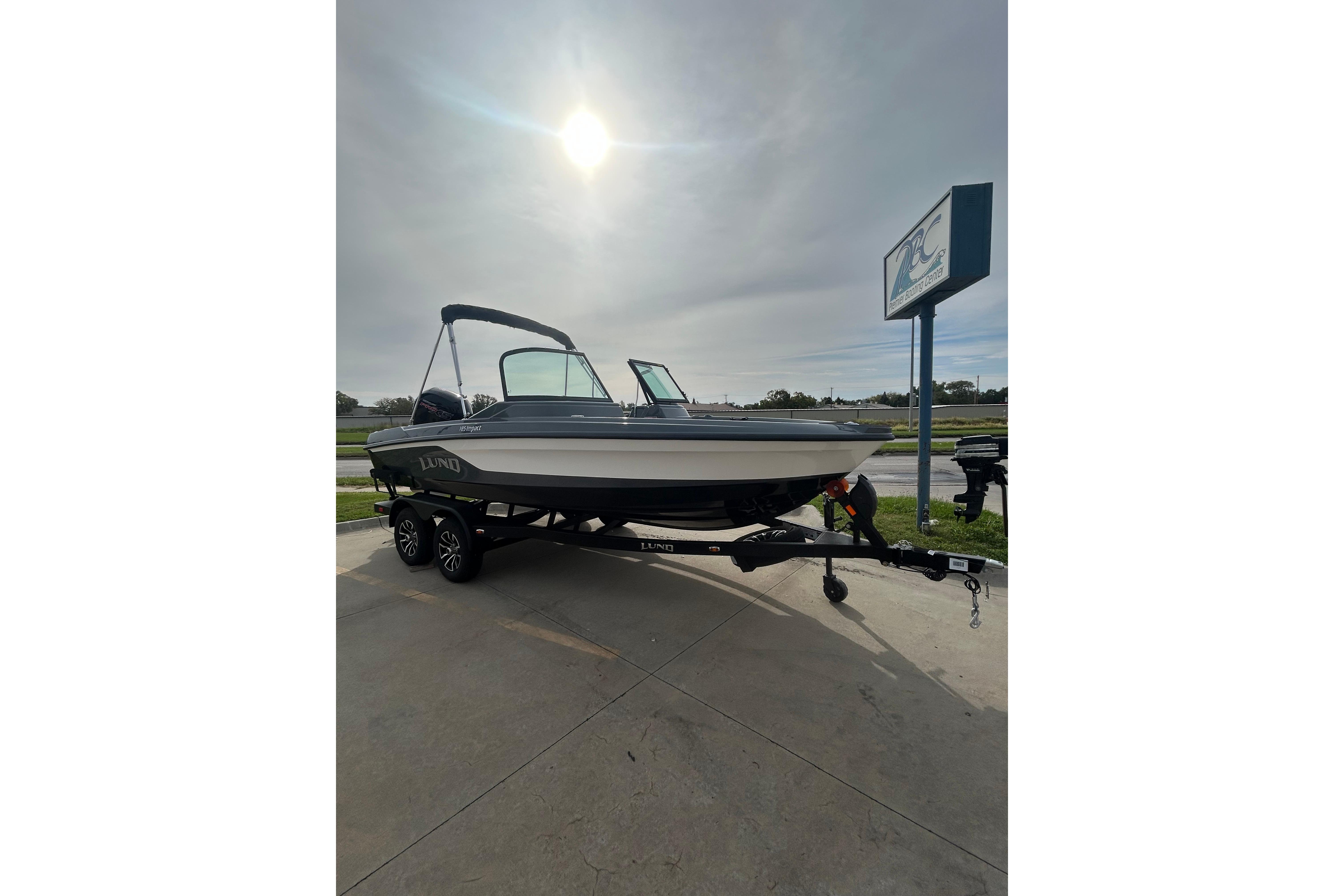 2026 Lund 185 Impact GL boat on trailer under sunny sky.