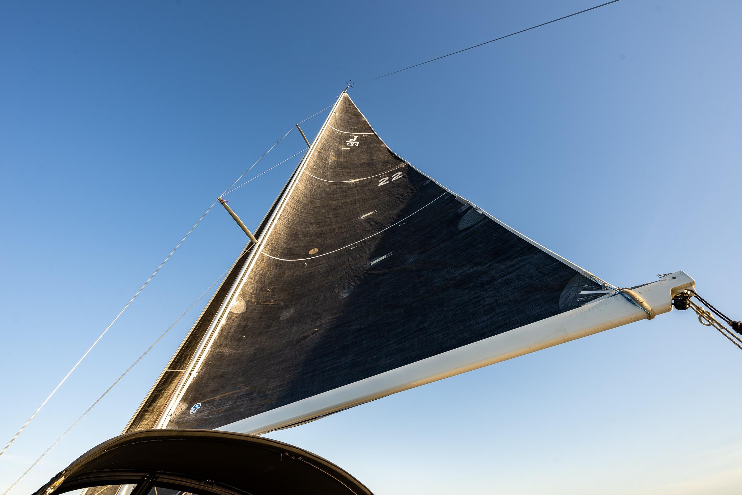 Sail of a 2007 J Boats J/124 yacht against a clear blue sky.