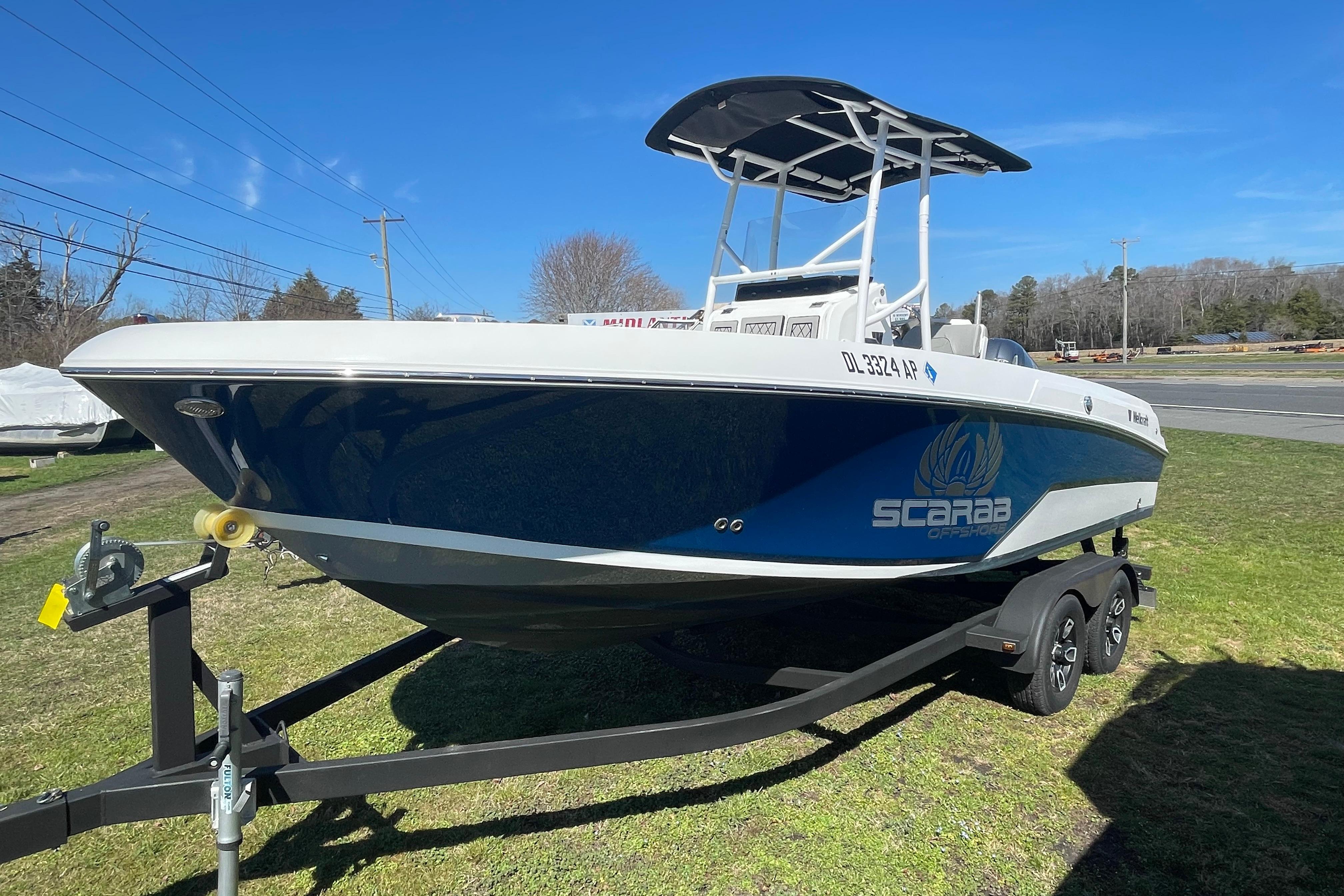 2022 Wellcraft 202 Fisherman boat on trailer, blue and white design, parked on grass.