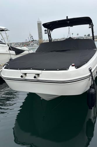2024 Bayliner DX 2250 boat docked with black cover, calm water background.