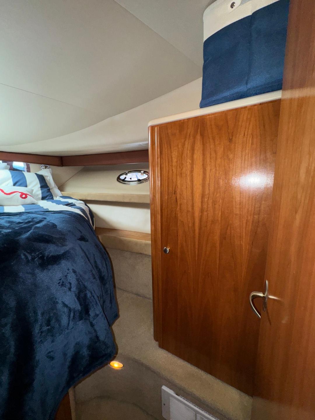 Interior cabin of 2003 Meridian 381 Sedan with wooden cabinetry and cozy bedding.