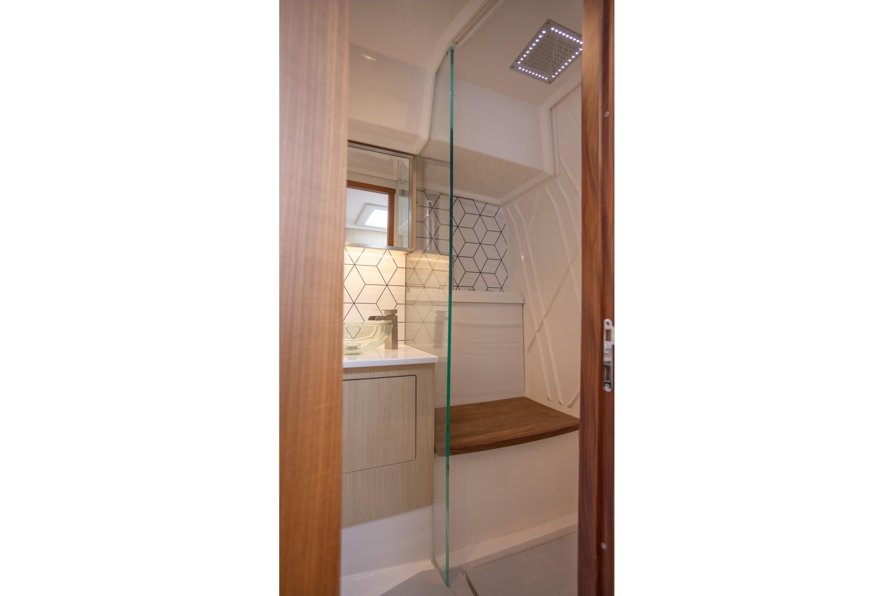 Modern bathroom in 2026 Regal LX43 yacht with glass shower and geometric tiles.