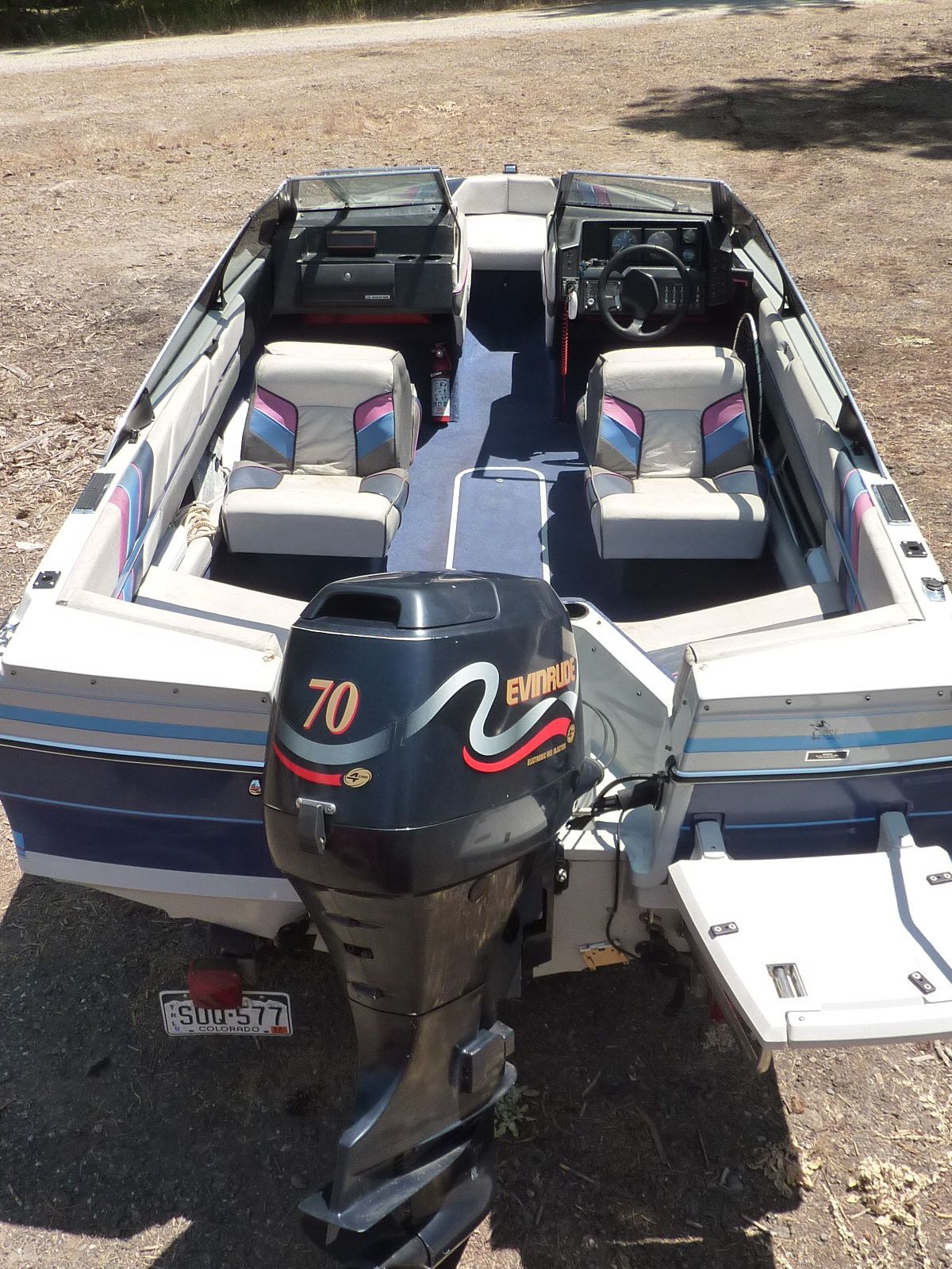 A 1989 Bayliner CAPRI with an Evinrude 70 HP outboard motor, parked on dry land.
