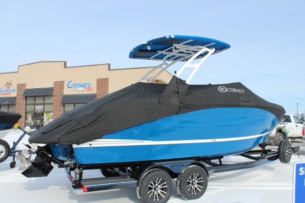 2025 Cobalt R6 boat, blue with black cover, on trailer outside dealership.