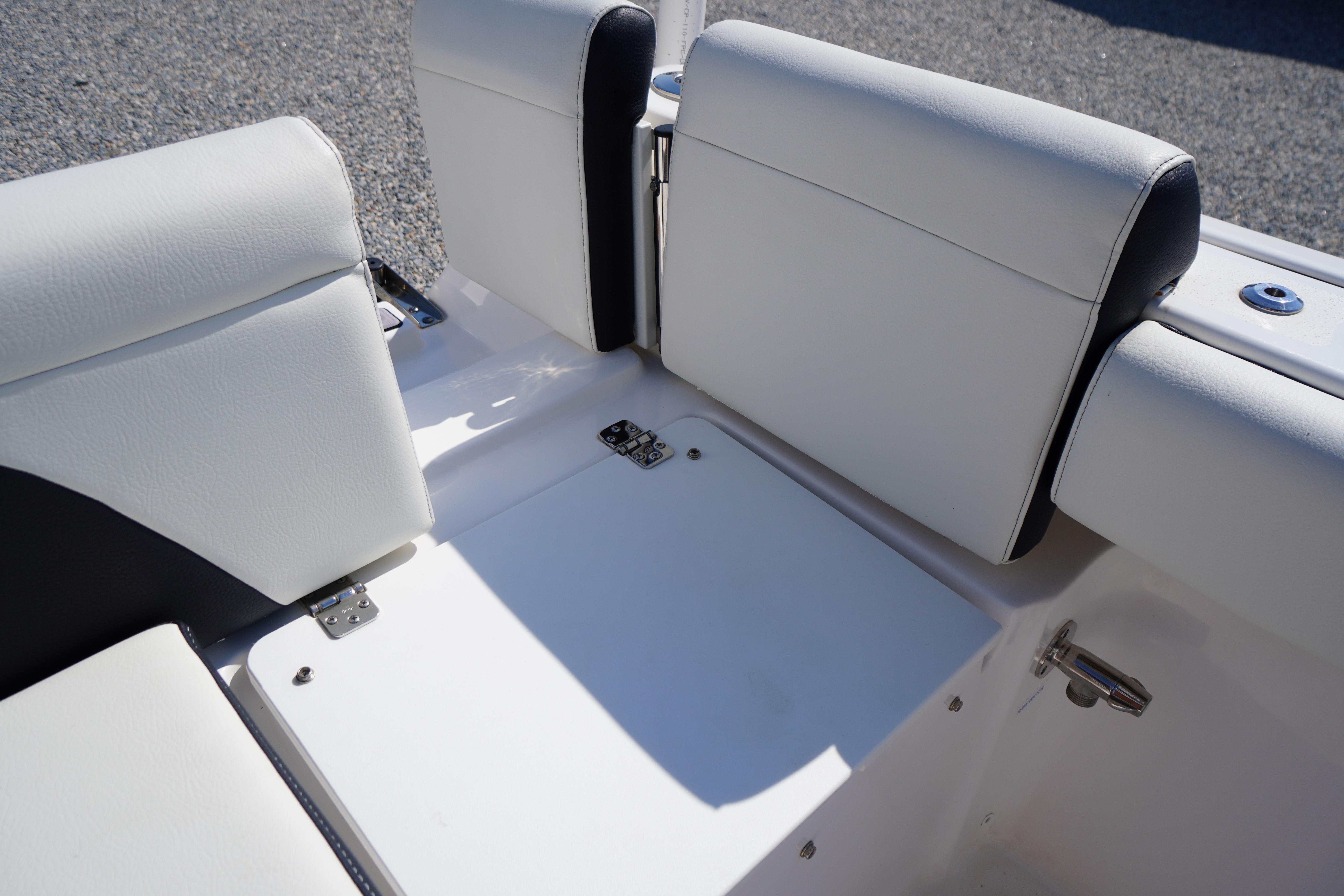 2025 Tidewater 232 SS boat seating area with white upholstery and storage compartment.