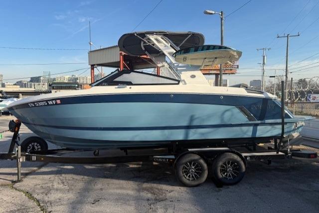 2023 Cobalt R6 Surf boat on trailer, blue and white design, parked outdoors.