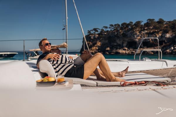 Man relaxing on Nautitech 44 Open yacht, 2025 model, with scenic coastal backdrop.
