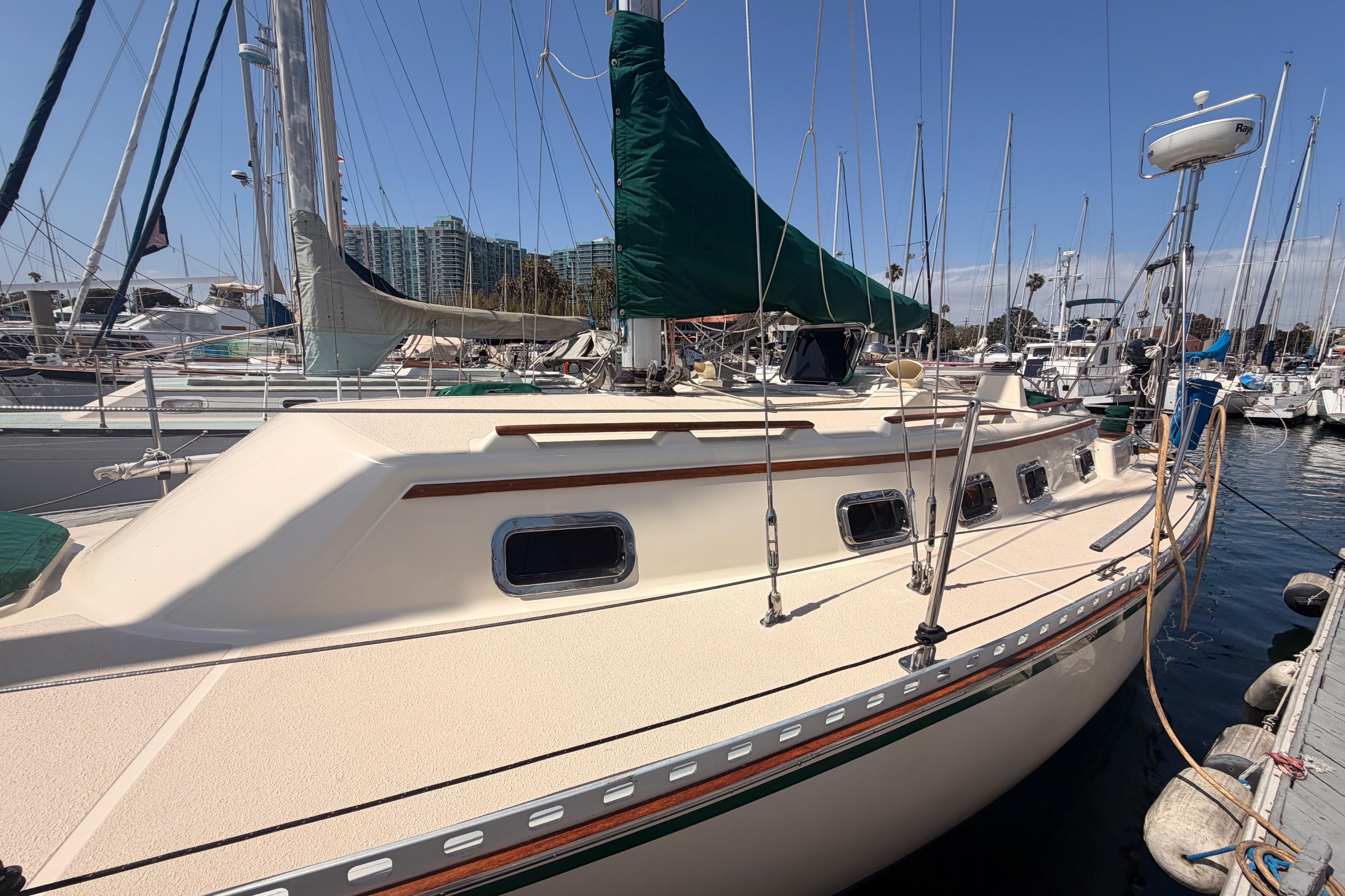 1991 Caliber 33 sailboat docked at marina, featuring green sail cover and multiple windows.