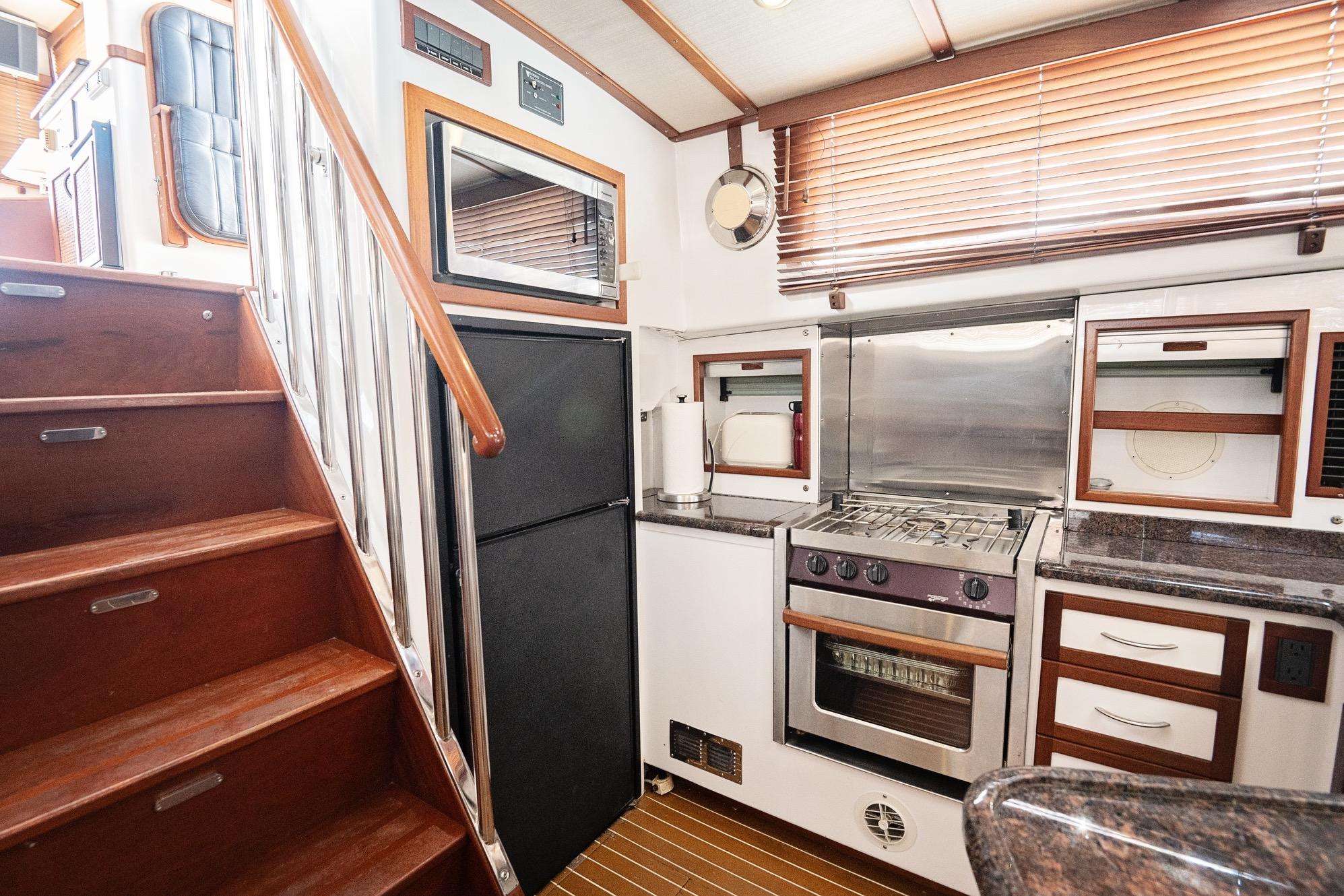 2007 Pilot Cruiser Expedition yacht kitchen with wooden stairs, modern appliances, and sleek cabinetry.