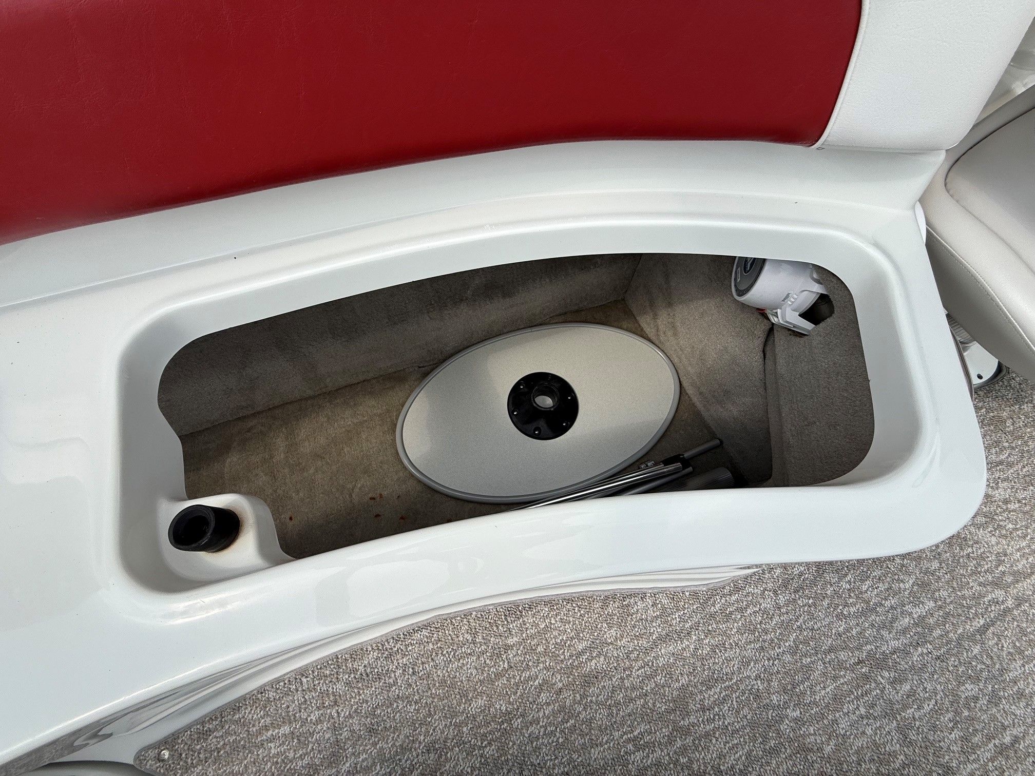 An open storage compartment with red upholstery and carpeted flooring.