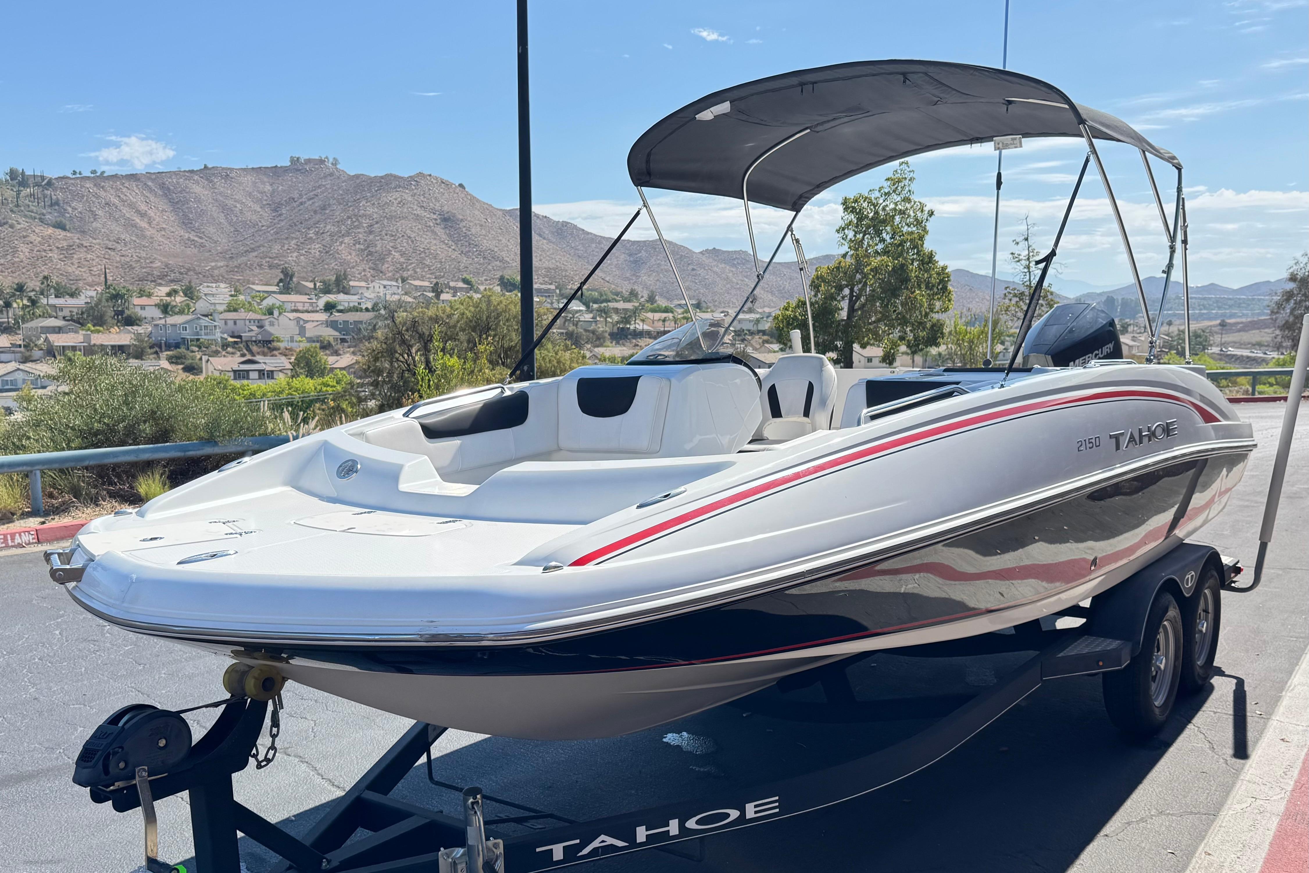 2019 Tahoe 2150 boat on trailer with canopy, parked near scenic hillside view.