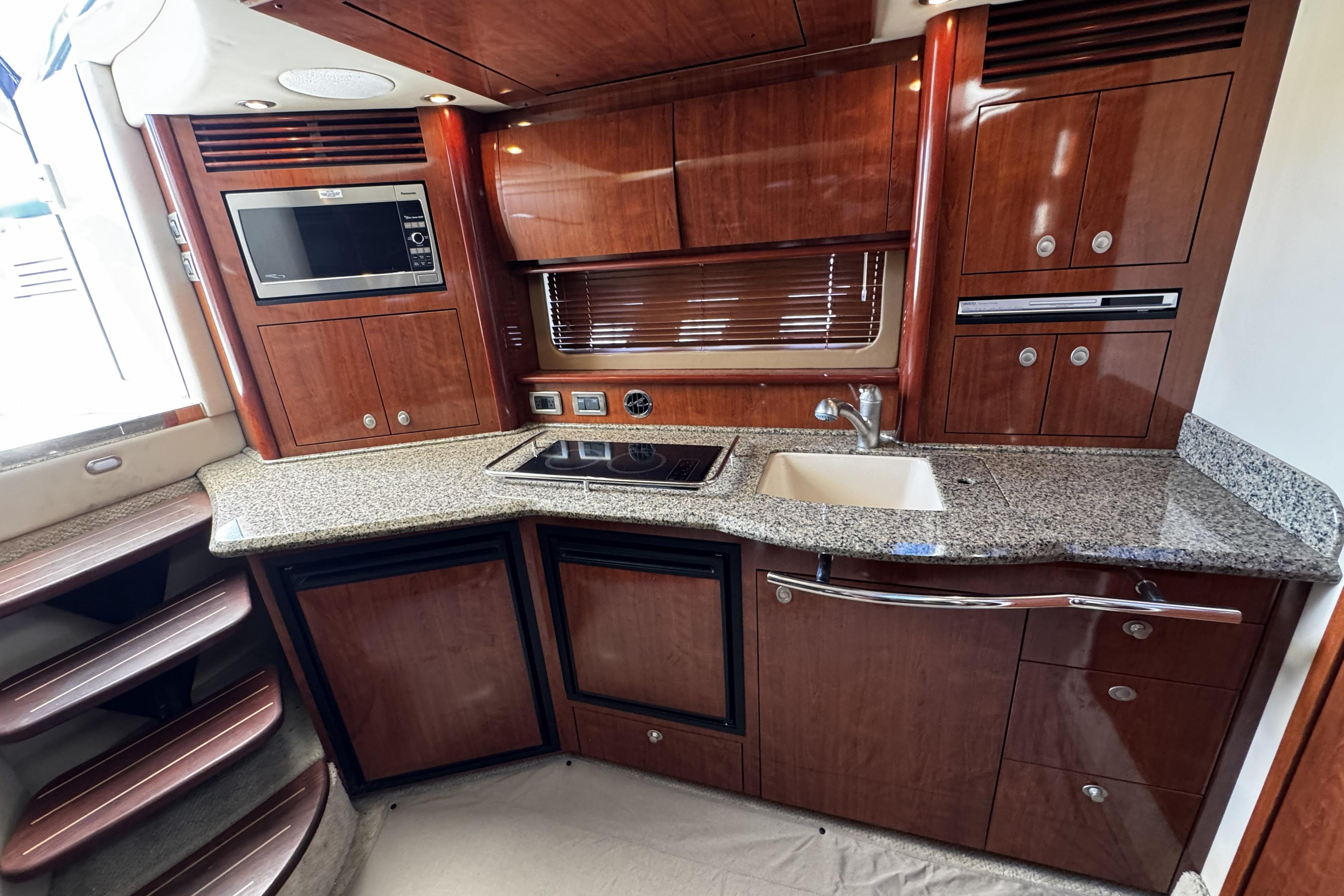Luxurious 2006 Sea Ray 40 Sundancer yacht kitchen with wood cabinetry and granite countertops.