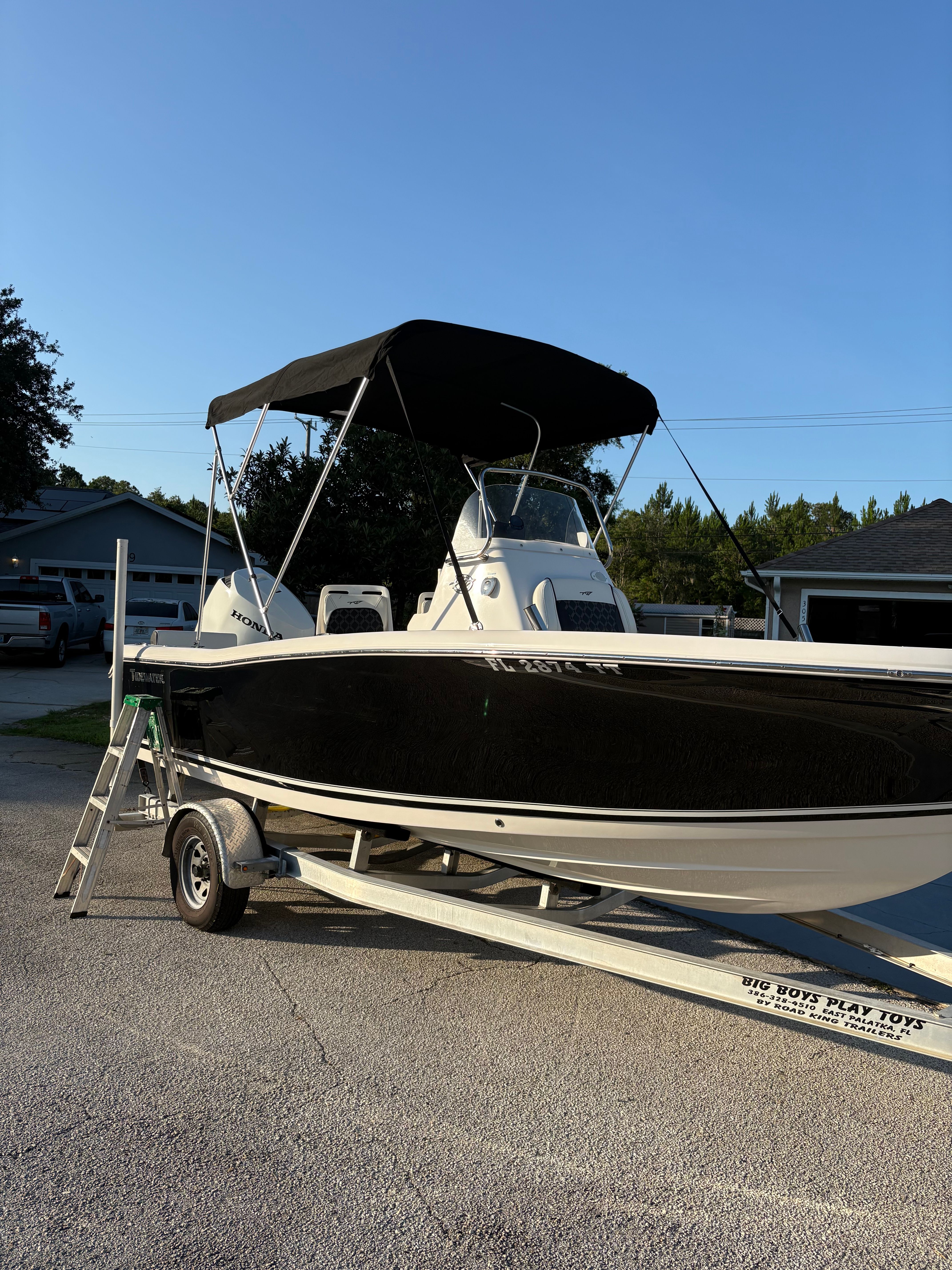 A 2024 Tidewater 198 CC Adventure boat on a trailer, featuring a black hull and bimini top.