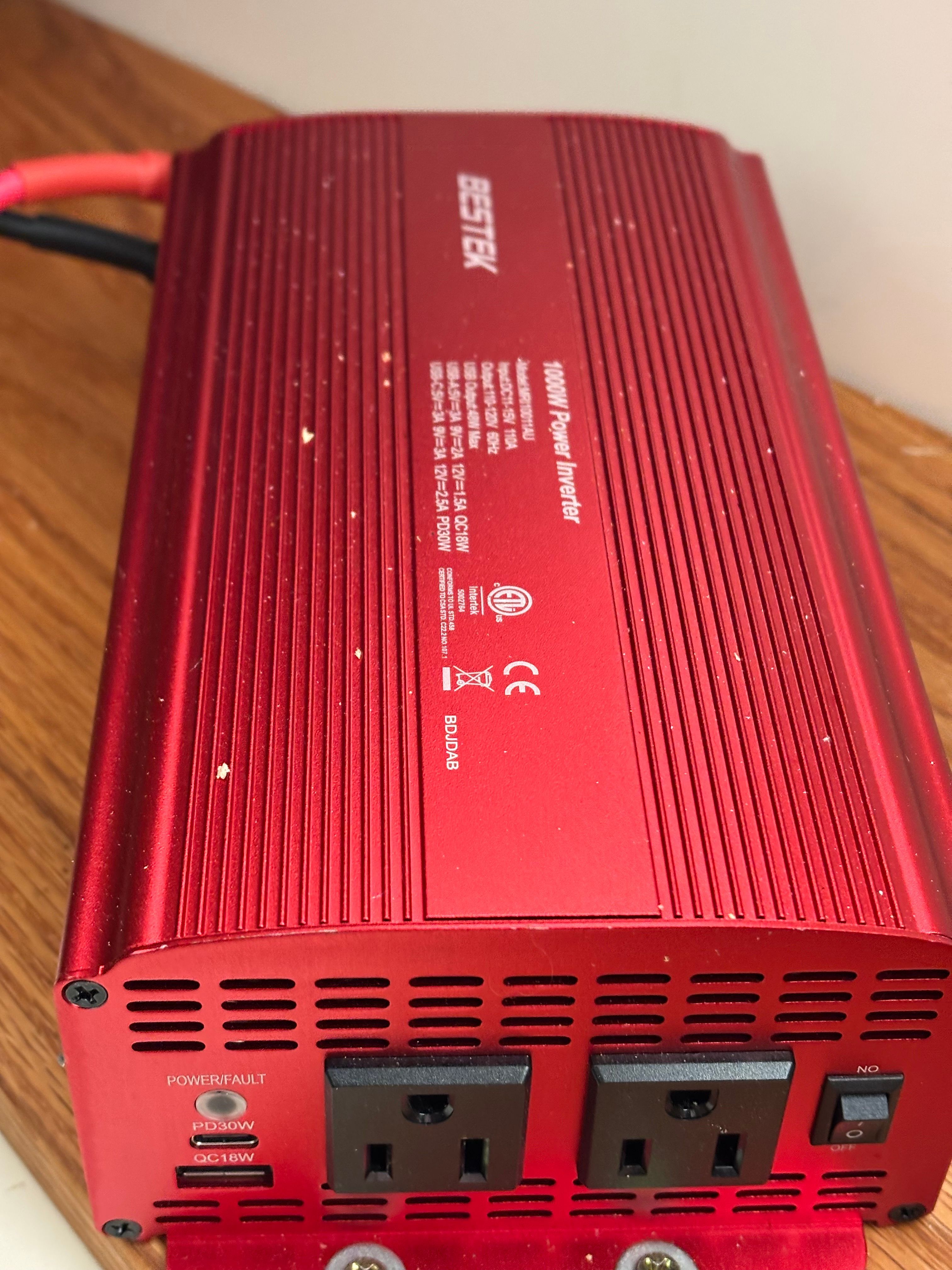 Red 1000W power inverter on wooden surface.
