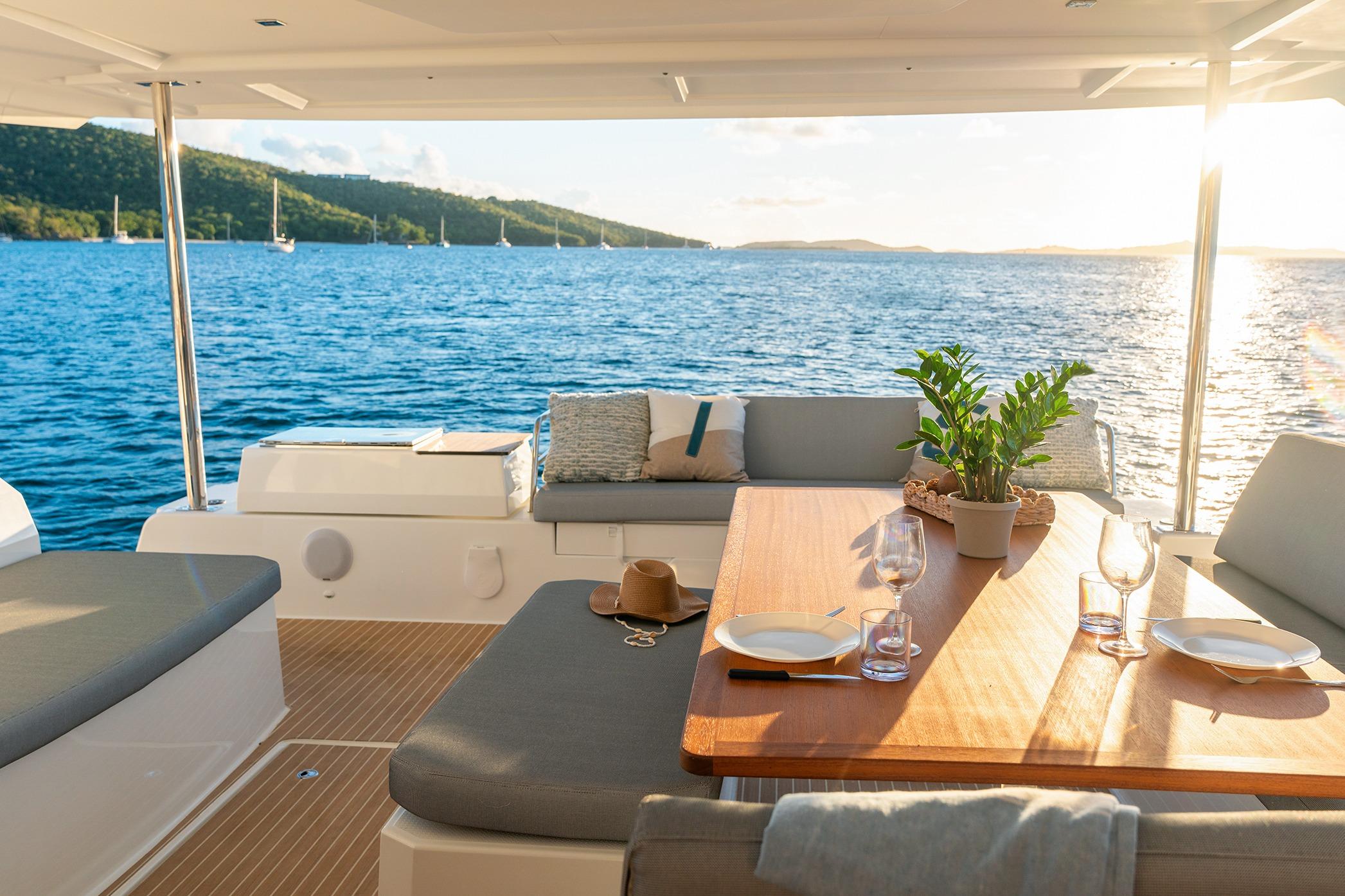 Luxurious 2026 Fountaine Pajot Aura 51 Catamaran deck with elegant dining setup at sunset.