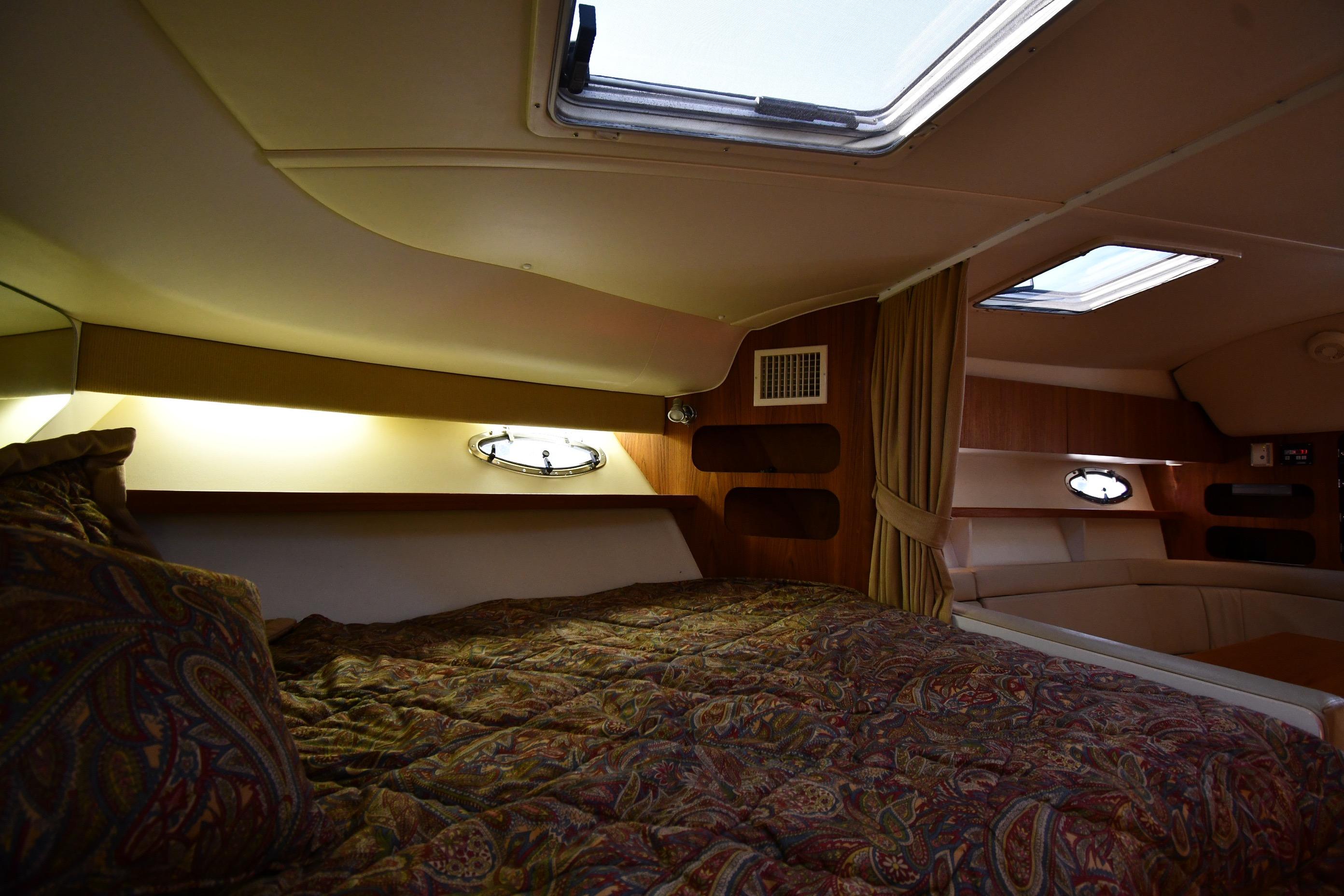 Cozy cabin interior of 1998 Tiara Yachts 3100 Open with patterned bedding and porthole windows.